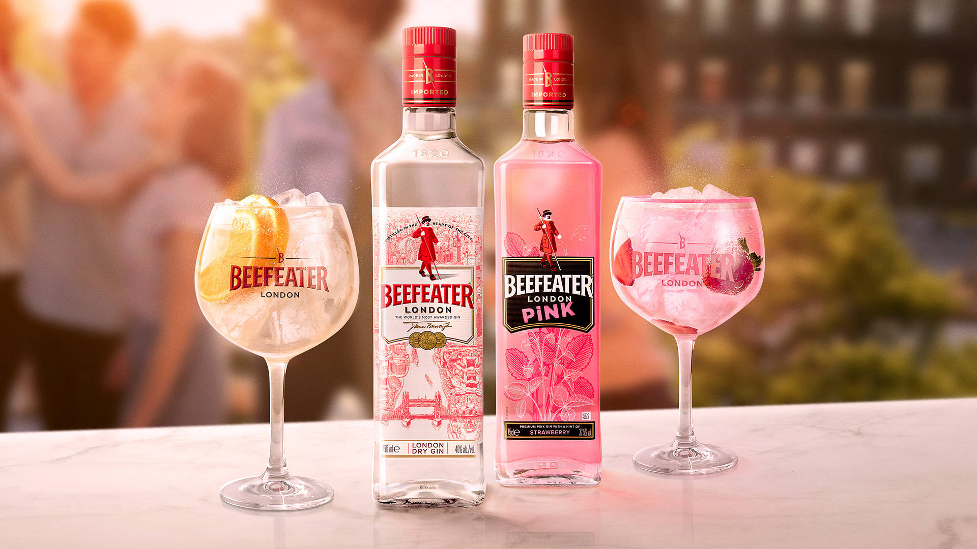 Gin 桌布 壁紙 — 兩瓶Beefeater琴酒和雞尾酒放在大理石吧檯上，背景有模糊的派對賓客，在溫暖的金色燈光下。