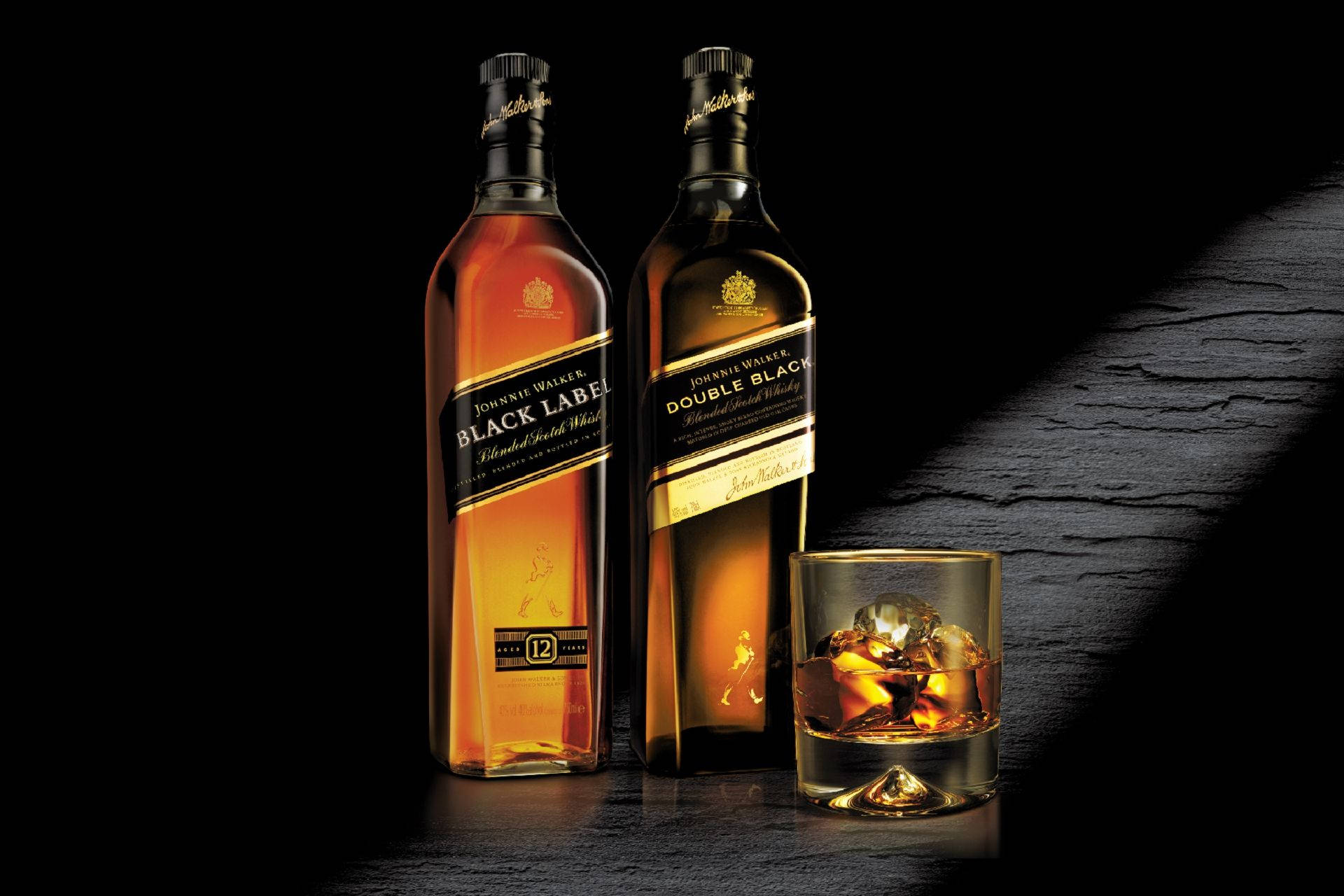bottle 桌布 壁紙 — 兩瓶Johnnie Walker威士忌和一杯加冰的玻璃杯放在黑暗有紋理的表面上，在戲劇性的燈光下。