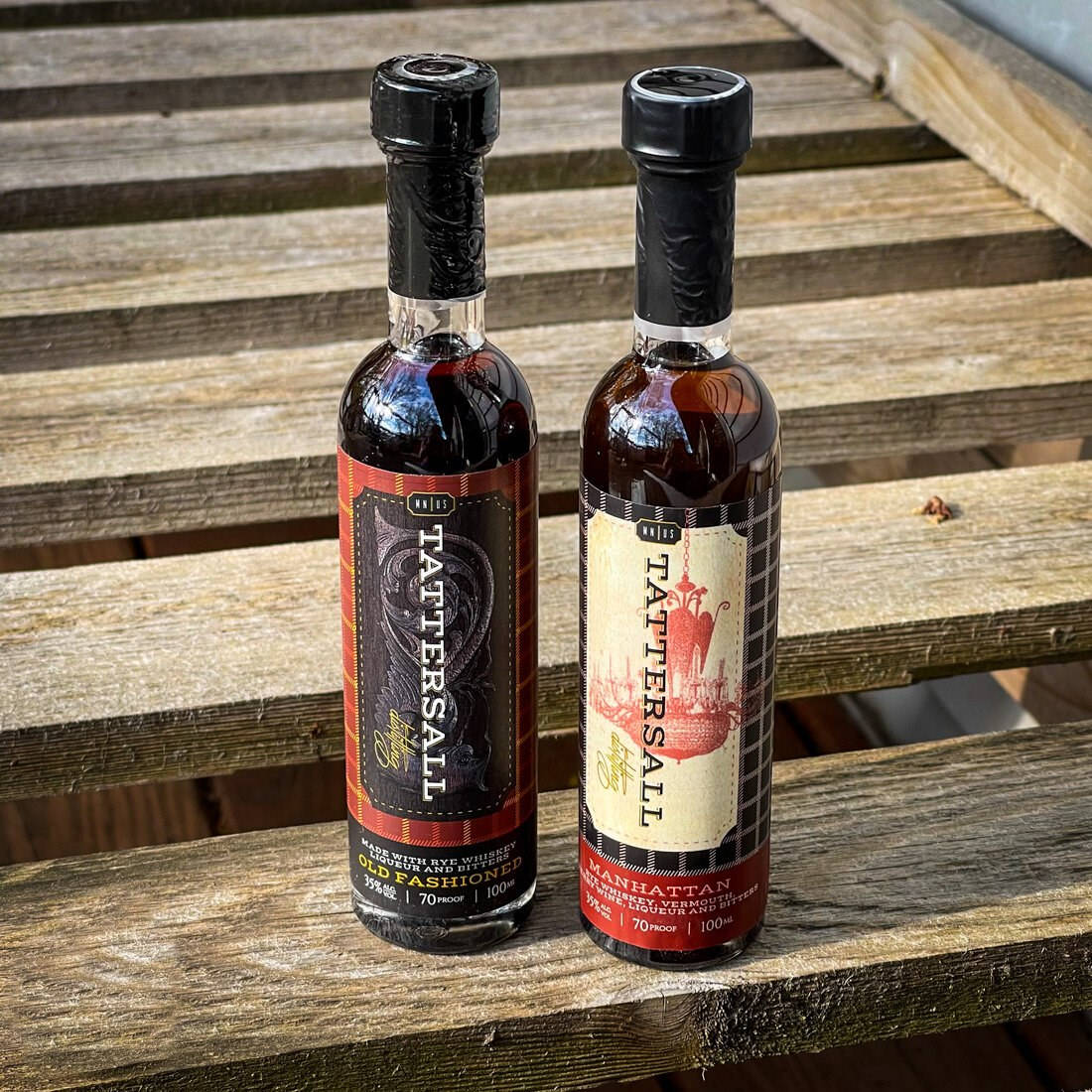 cocktail 桌布 壁紙 — 兩瓶Tattersall雞尾酒並排放在經風化的木條上，在明亮的日光下。