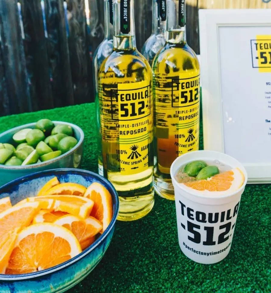 drinks 桌布 壁紙 — 兩瓶Tequila 512 reposado放在綠色草地上，旁邊有碗裝青檸和橙片，以及品牌飲具。