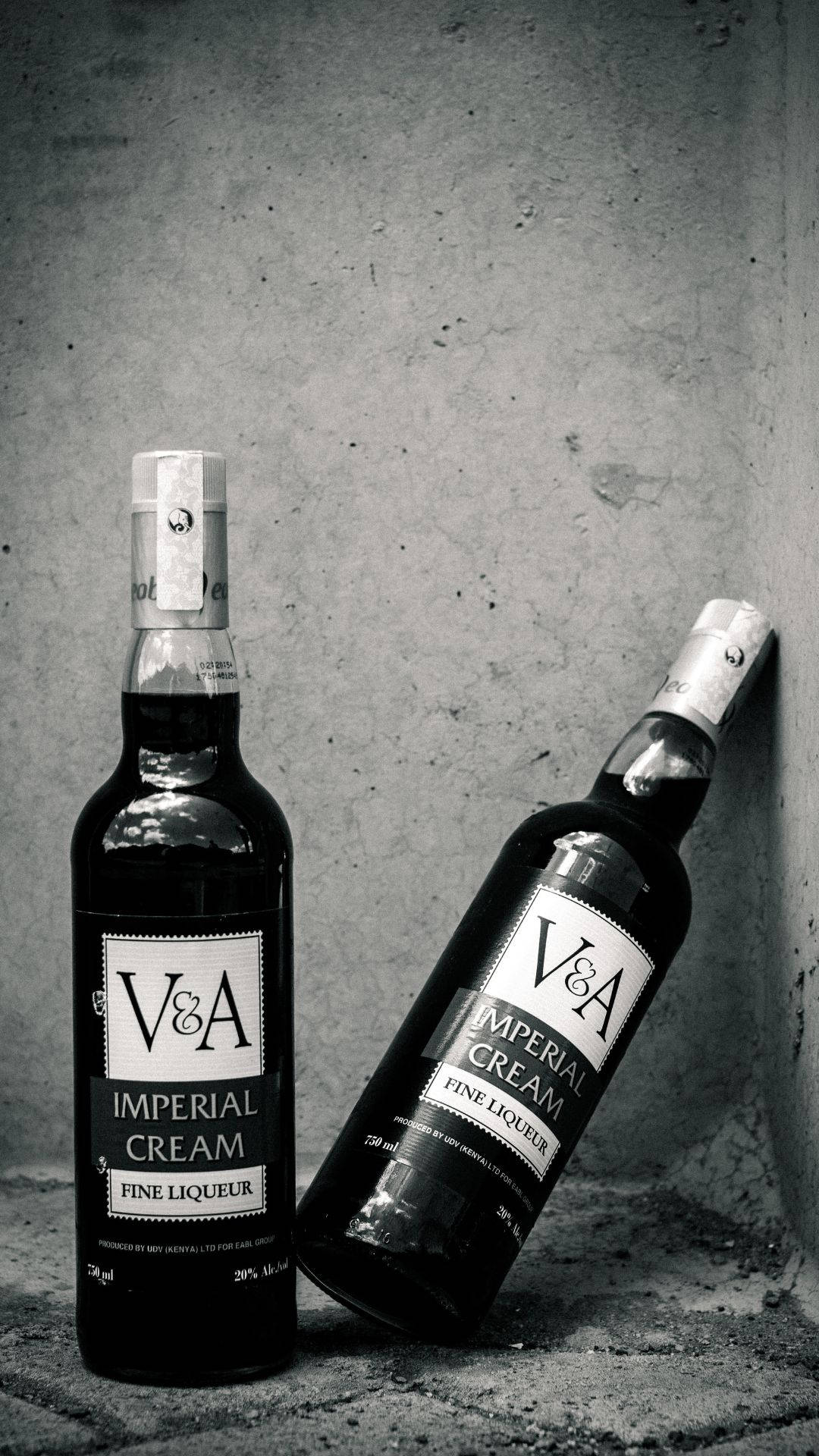 alcohol 桌布 壁紙 — 兩瓶V&A Imperial Cream利口酒，一瓶直立，一瓶靠著紋理混凝土牆，單色調。