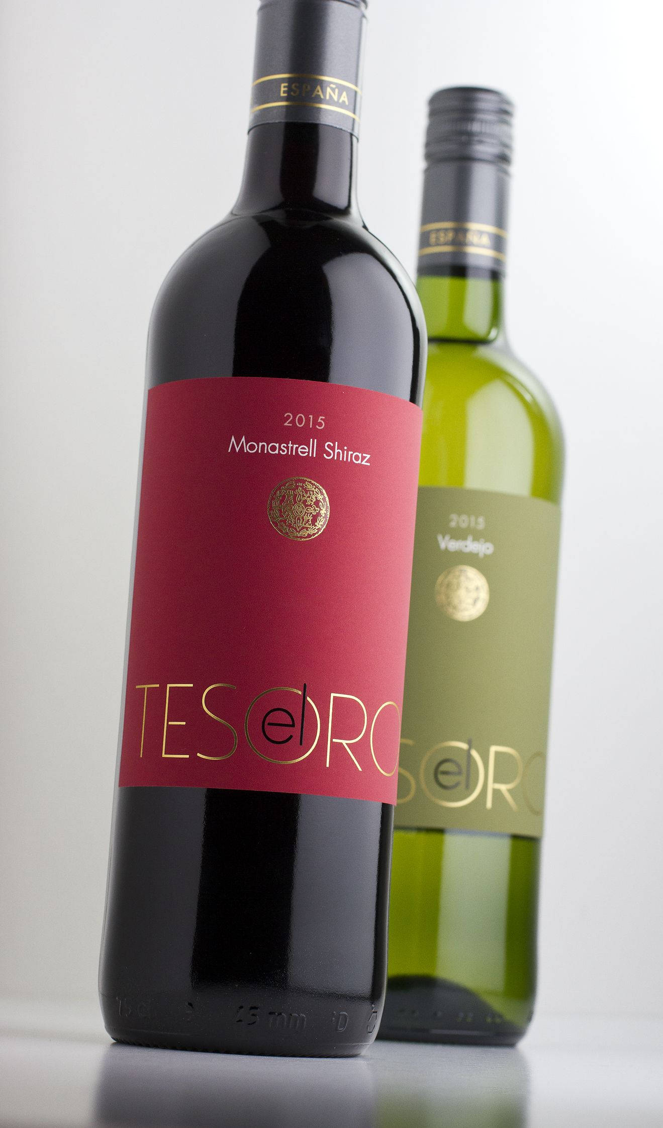 alcohol 桌布 壁紙 — 兩瓶優雅的葡萄酒，一瓶紅色標籤的Tesoro Monastrell Shiraz和一瓶綠色標籤的Tesoro Verdejo，立在潔白的背景前。