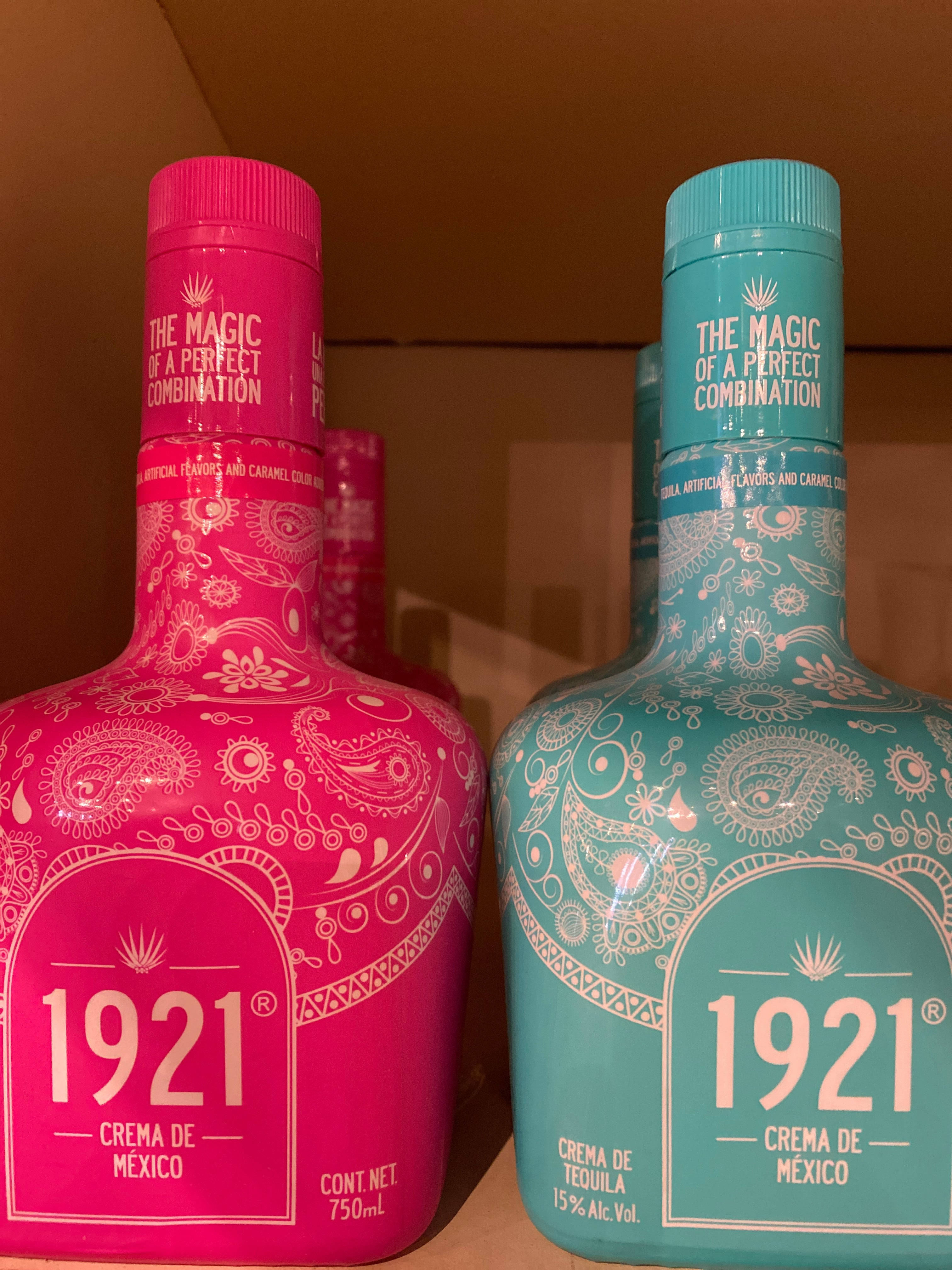 drinks 桌布 壁紙 — 兩瓶色彩鮮豔的1921 Crema de Tequila，粉紅色和藍綠色，帶有複雜的白色圖案，並排放在一個紙板箱中。