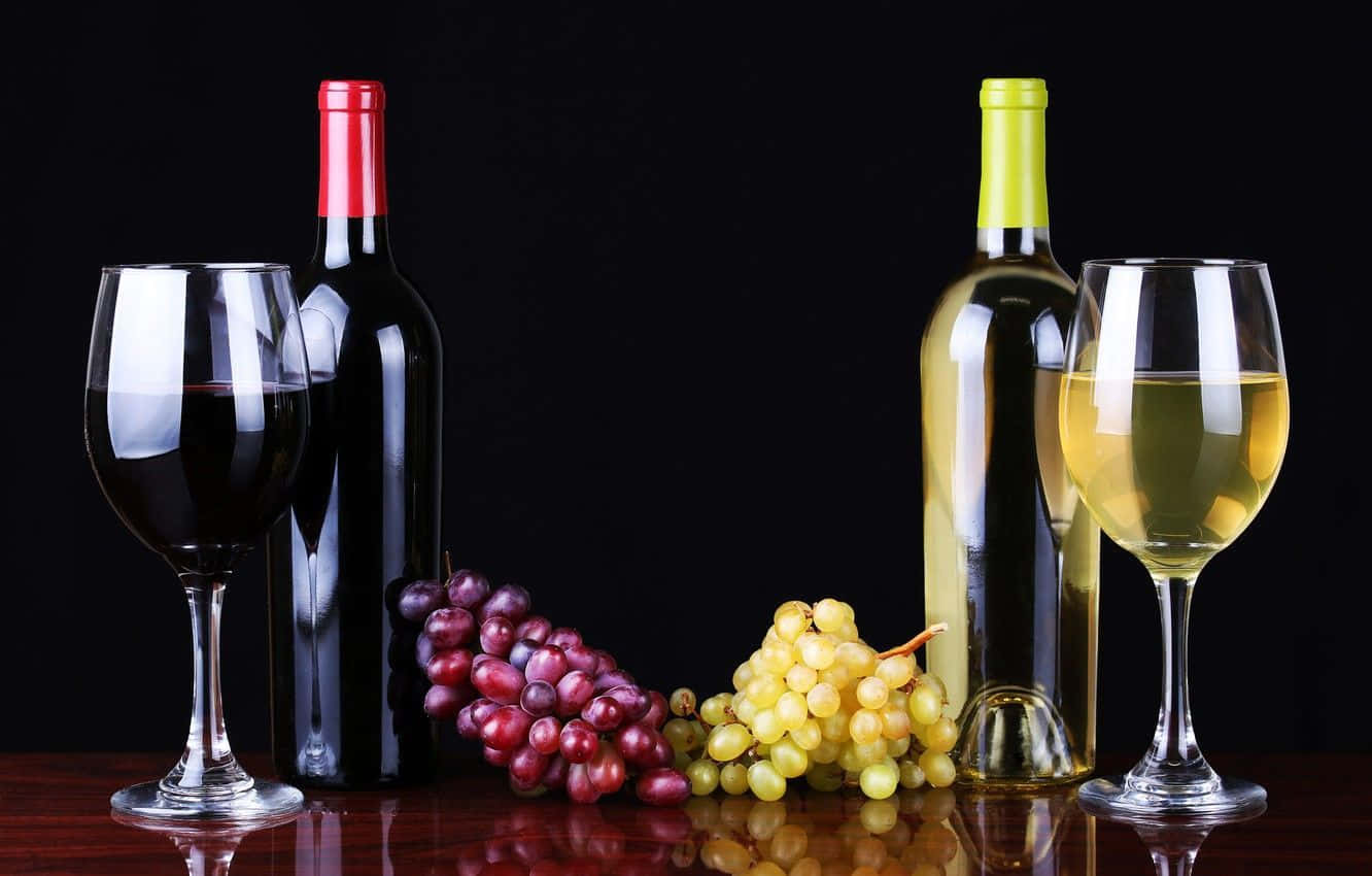 White Wine 桌布 壁紙 — 兩瓶葡萄酒和酒杯，搭配紅葡萄和青葡萄，置於深色反光表面上。