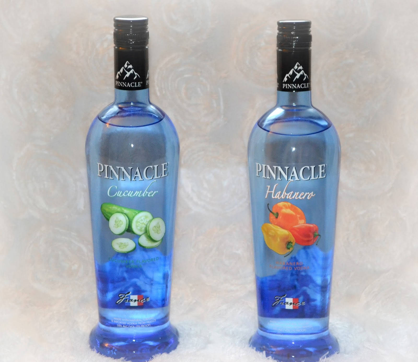 bottle 桌布 壁紙 — 兩瓶藍色Pinnacle伏特加，一瓶小黃瓜口味，一瓶哈瓦那辣椒口味，並排放在有紋理的白色表面上。
