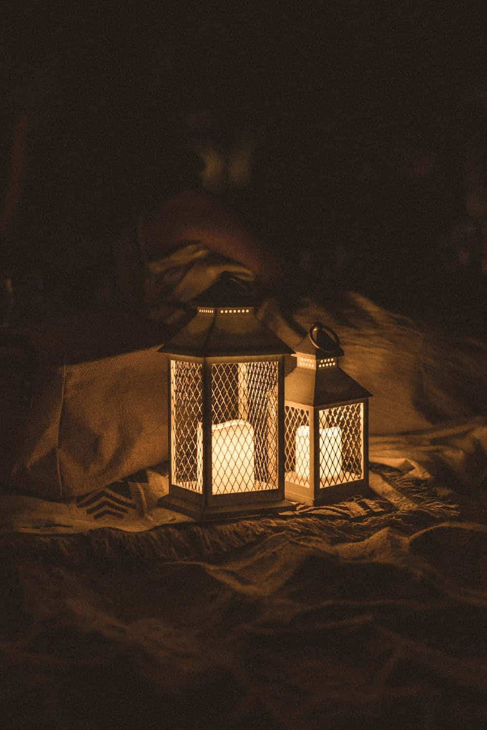 Ramadan 桌布 壁紙 — 兩盞發光的燈籠發出溫暖的光，在黑暗舒適的環境中，在皺巴巴的布料上投下柔和的陰影。