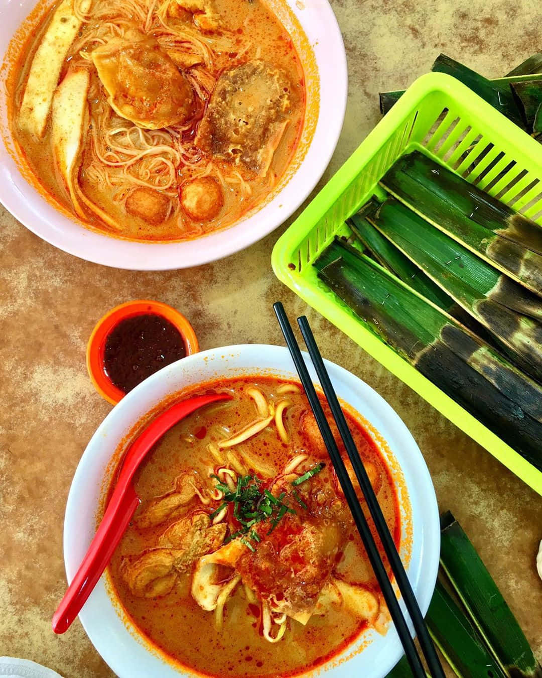Delicious Food 桌布 壁紙 — 兩碗熱氣騰騰的濃味蟹肉麵湯，配以裝飾，旁邊放著一個裝有香蕉葉的綠色籃子，放在鄉村風格的桌面上。