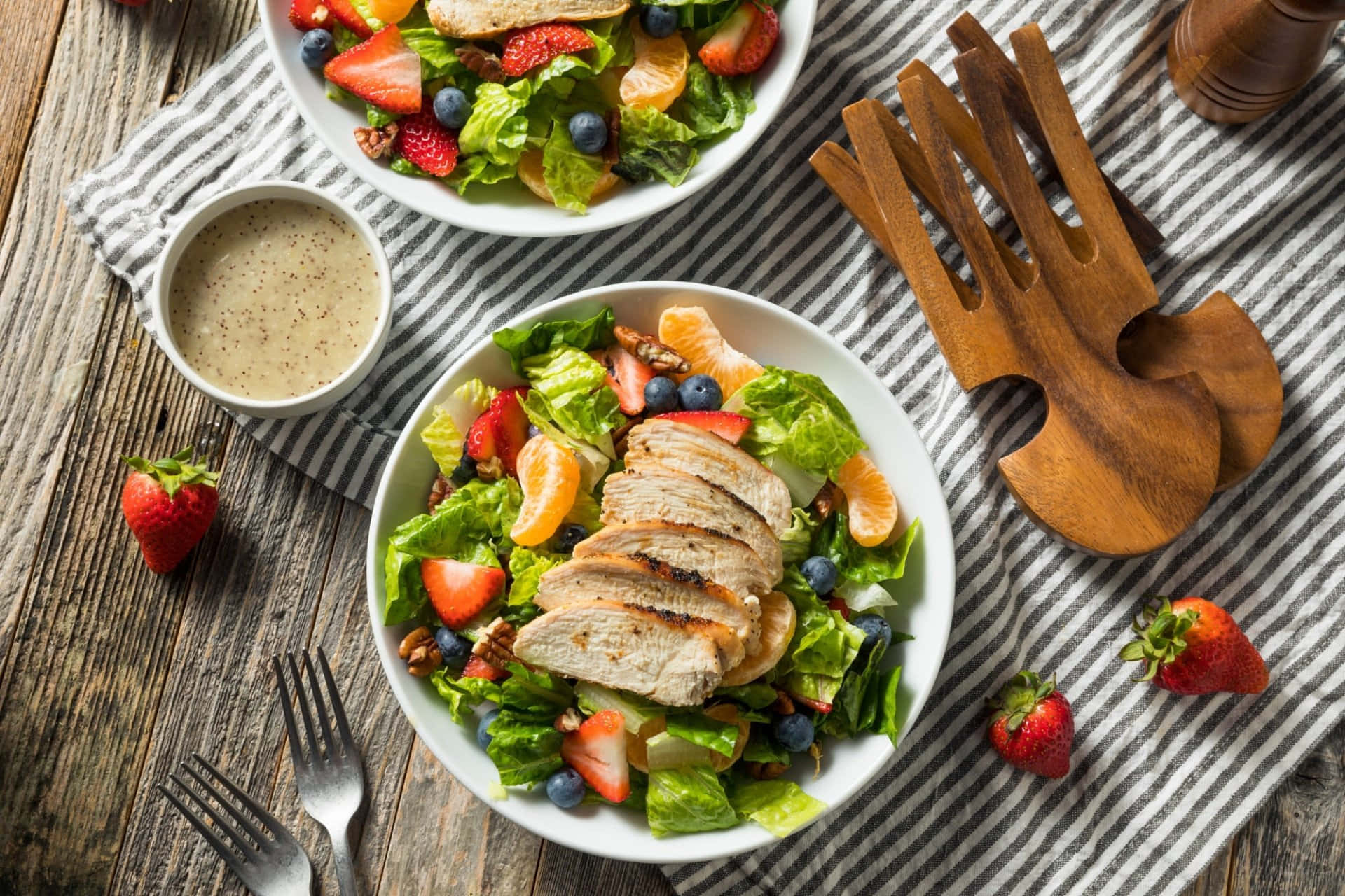 沙拉 桌布 壁紙 — 兩碗色彩繽紛的雞肉沙拉，搭配草莓、藍莓和柳橙，放在質樸的木桌上。