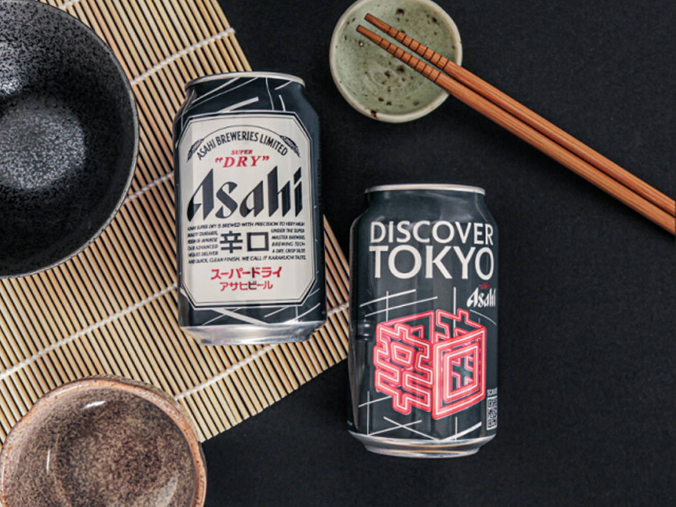 竹蓆上的兩罐Asahi啤酒罐，配陶瓷碗和筷子。 — 大阪 壁紙