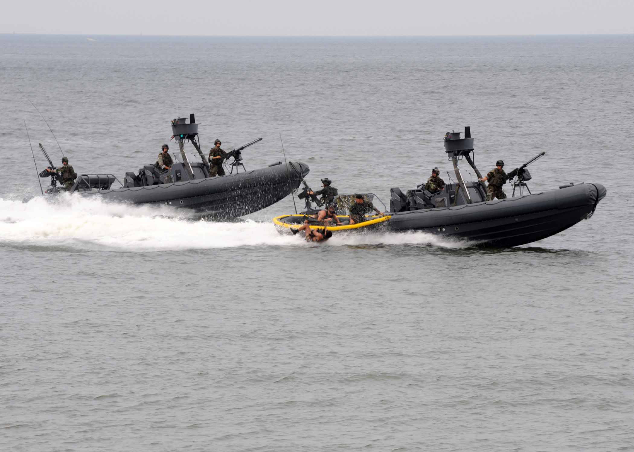 u s navy 桌布 壁紙 — 兩艘黑色軍用快艇載著武裝士兵在灰色海面上飛馳，激起白色浪花。