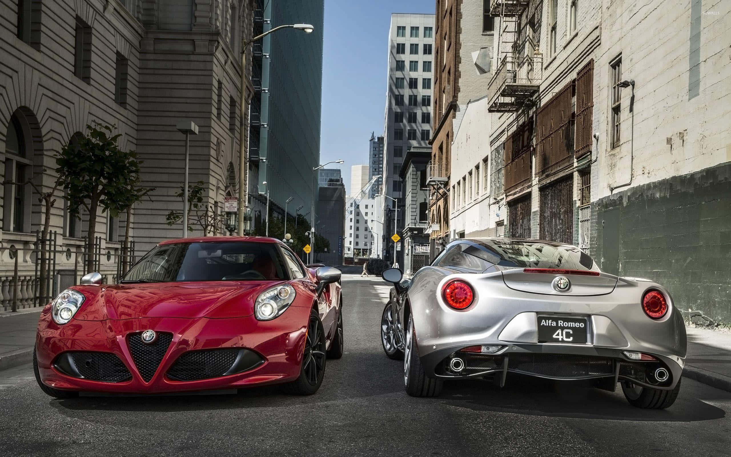 Alfa Romeo 4c 桌布 壁紙 — 兩輛Alfa Romeo 4C跑車，一輛紅色正面，一輛銀色背面，停放在高樓大廈之間陽光普照的城市街道上。