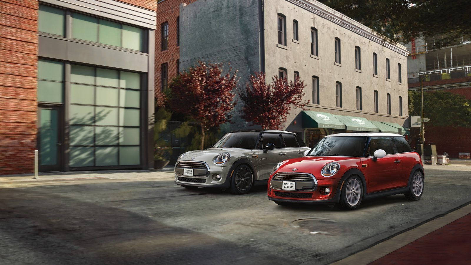 Mini Cooper 桌布 壁紙 — 兩輛MINI Cooper汽車銀色和紅色停放在城市的街道上，旁邊是磚砌建築和秋天的樹木。