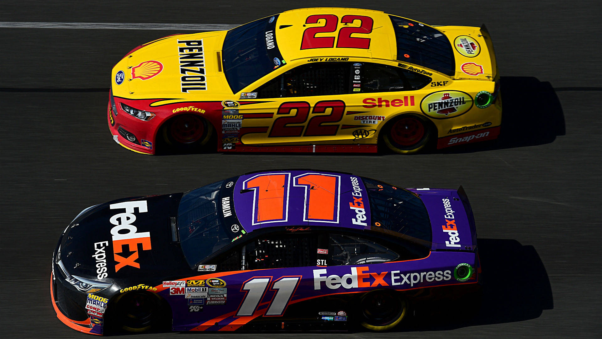 Denny Hamlin 桌布 壁紙 — 兩輛NASCAR賽車，號碼22和11，在明亮的日光下在賽道上並排飛馳。