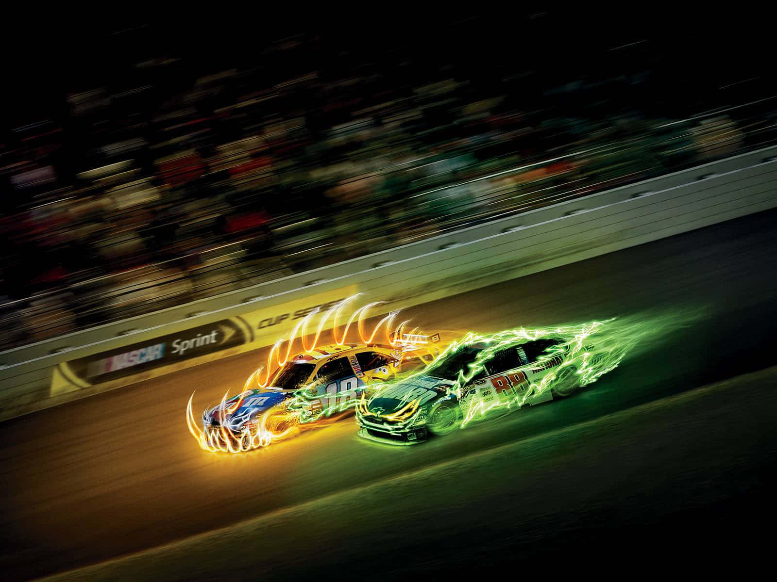 nascar 桌布 壁紙 — 兩輛NASCAR賽車在夜間並排疾馳，發出橙色和綠色的發光火焰軌跡，背景是模糊的人群。