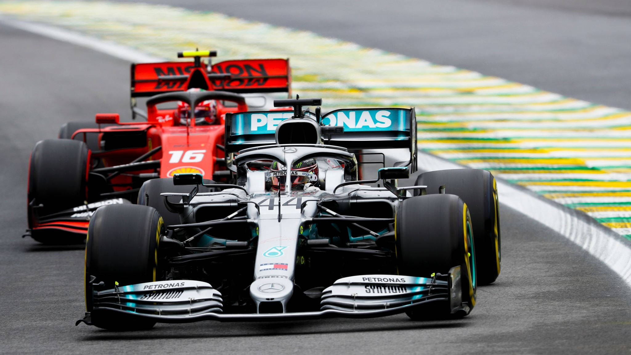 Formula One 桌布 壁紙 — 兩輛一級方程式賽車在濕滑賽道上緊密競賽，賽道有黃色和綠色路緣石。