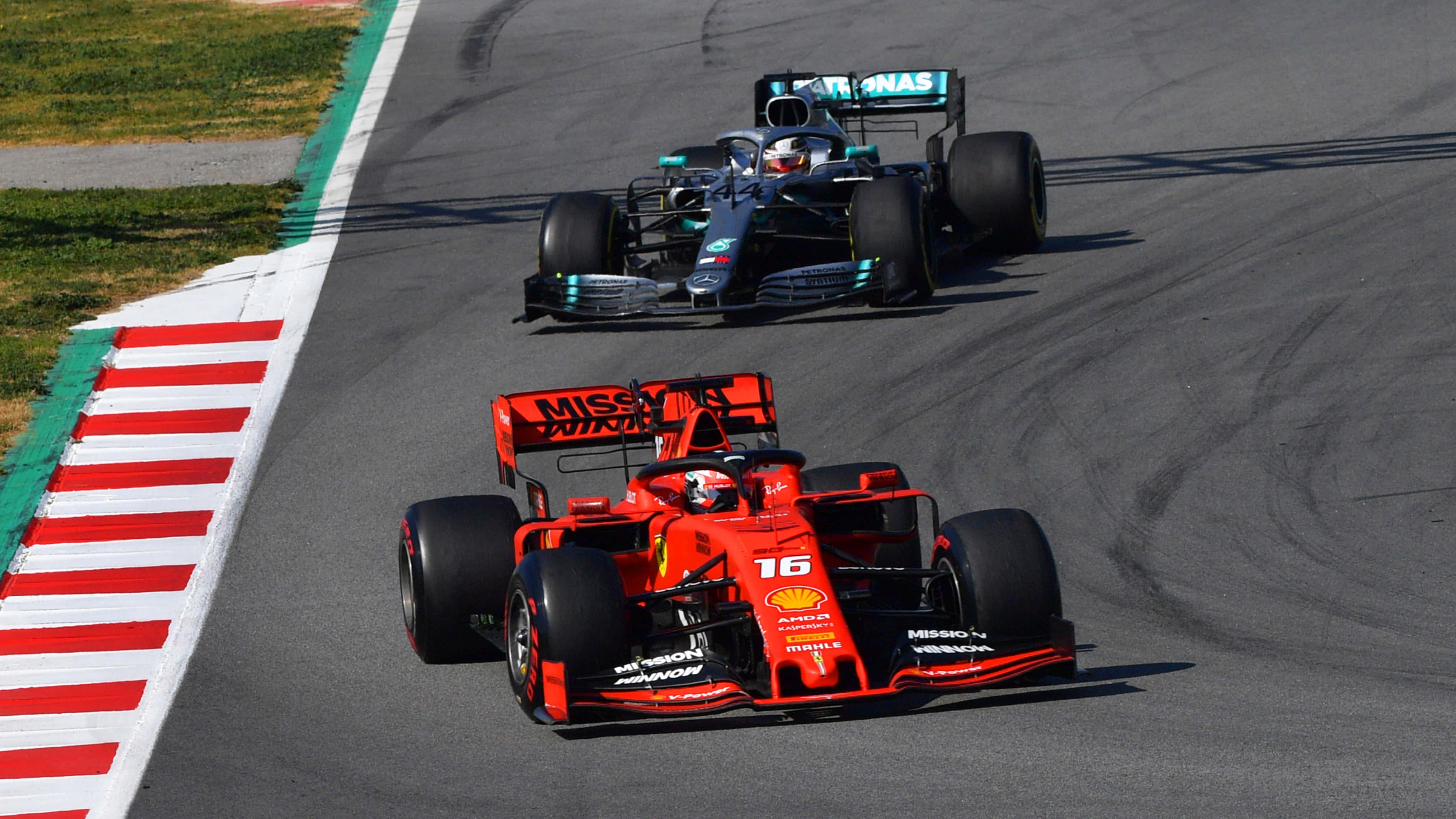 F1 2019 壁紙 桌布 壁紙 — 兩輛一級方程式賽車在陽光普照的賽道上緊密競賽，賽道設有紅、白、綠色路肩。