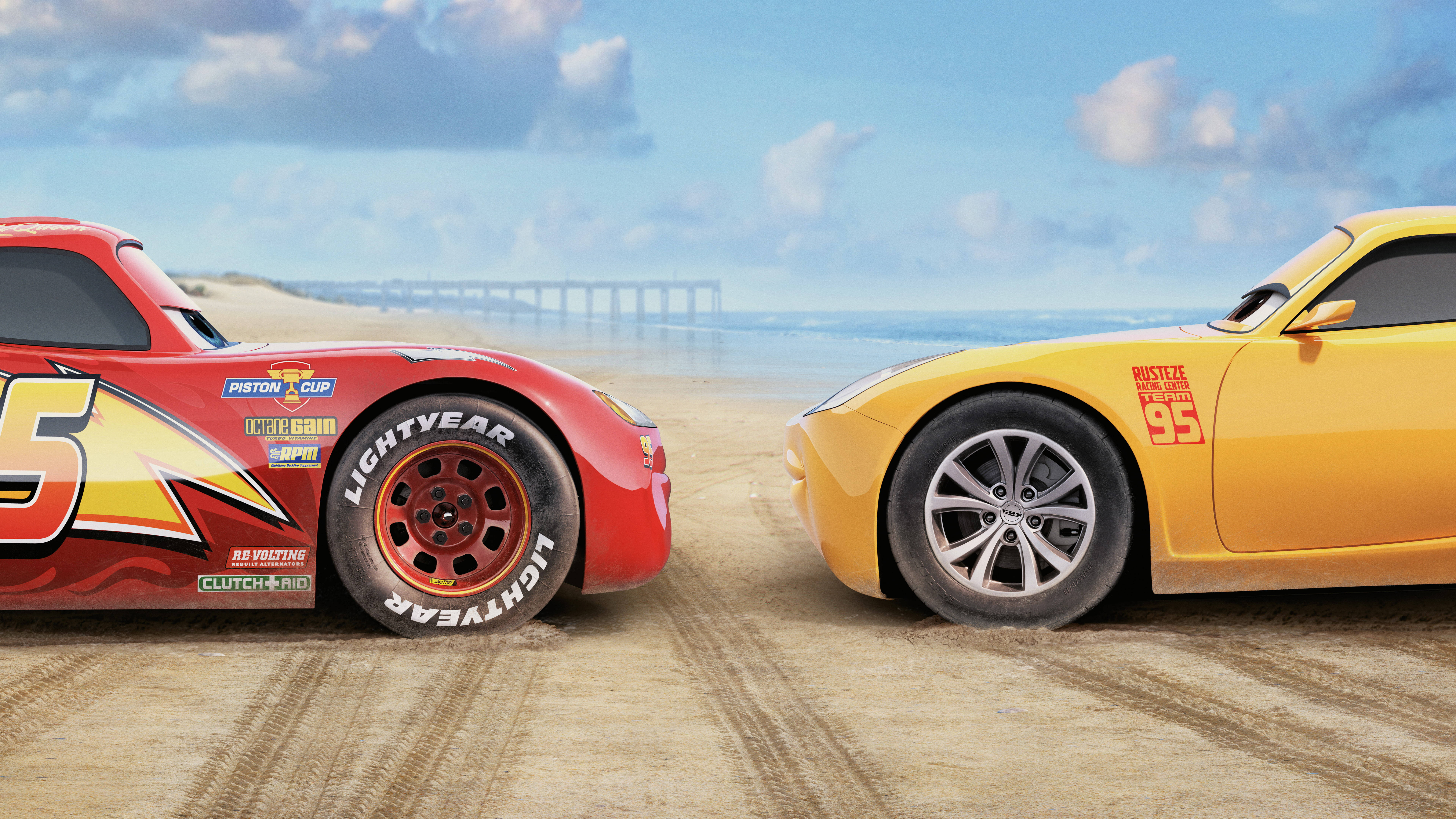 Pixar 桌布 壁紙 — 兩輛動畫賽車在沙灘上對峙，背景有海洋和碼頭，藍天白雲。