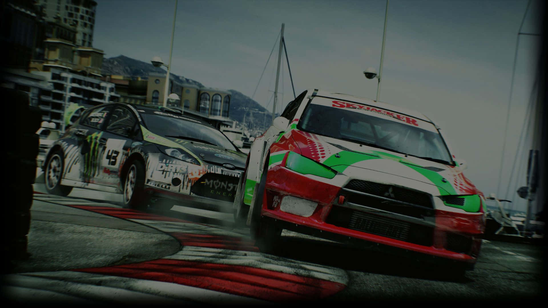 1080p Dirt 3 桌布 壁紙 — 兩輛拉力賽車在沿海賽道上激烈飄移，背景是霧氣繚繞的山脈和城市建築。