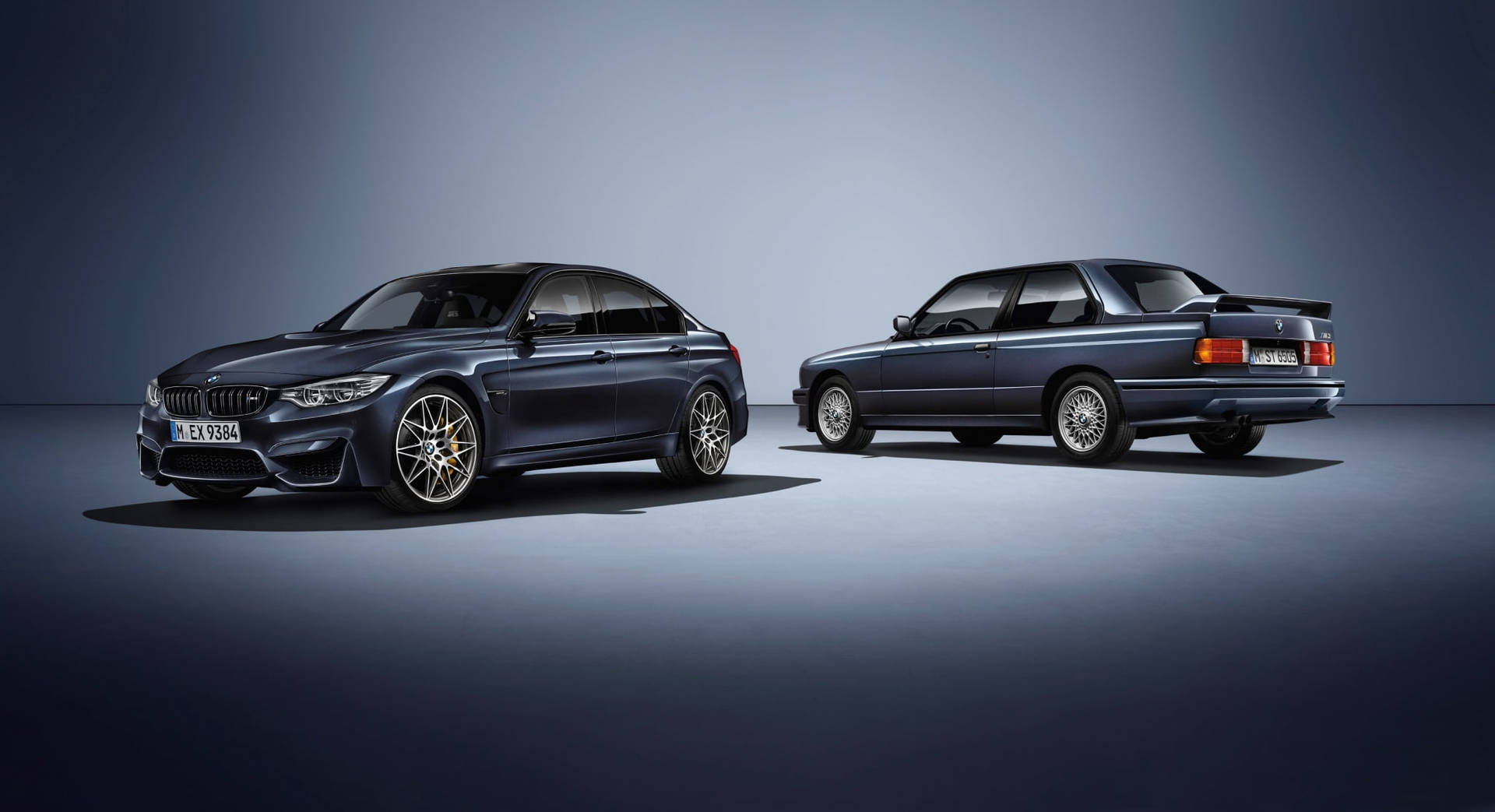 BMW 動圖 桌布 壁紙 — 兩輛時尚深藍色BMW轎車，現代與經典型號，在極簡風格的工作室中以戲劇性燈光展示。