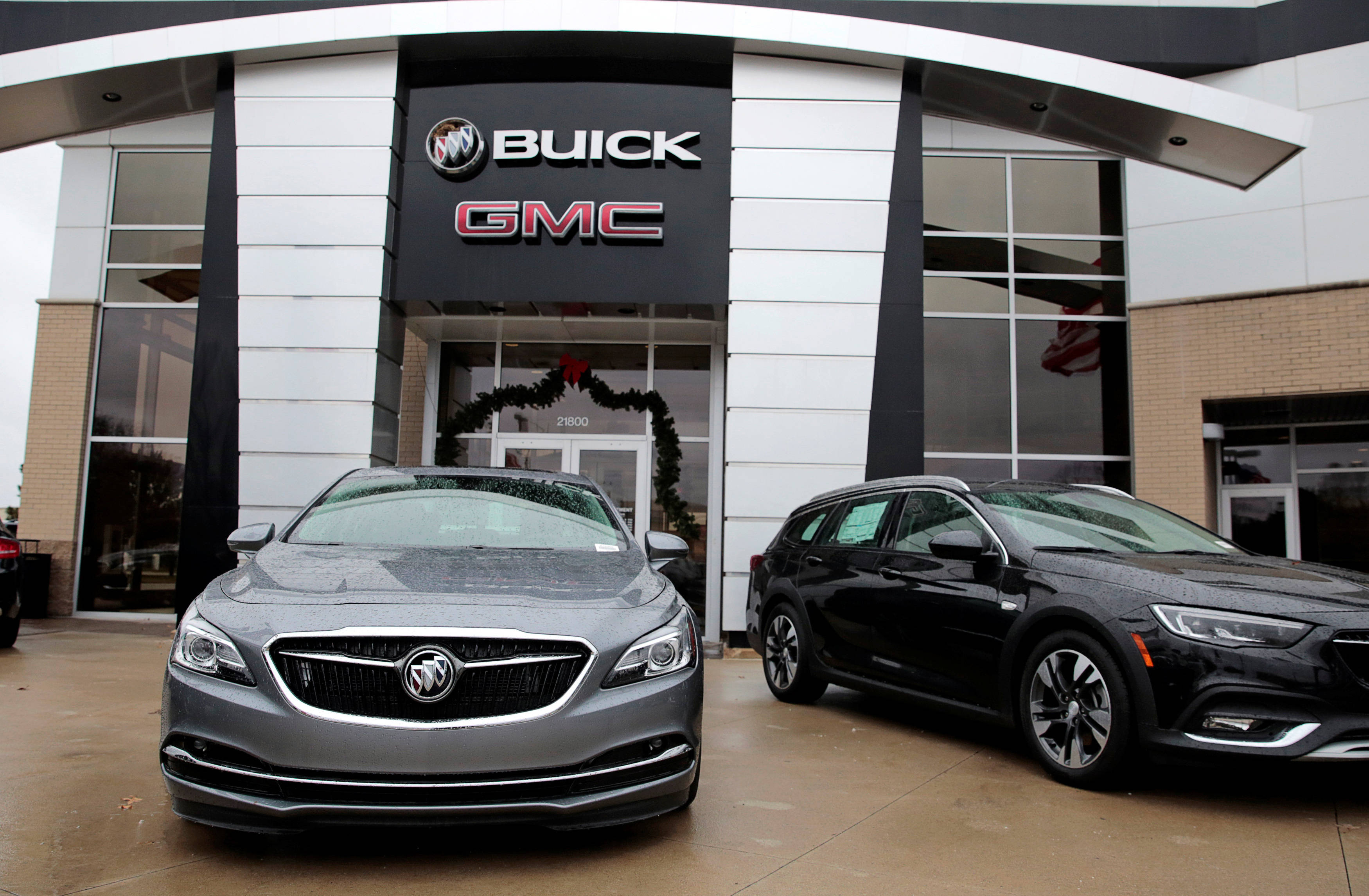 Buick 桌布 壁紙 — 兩輛時尚現代汽車，灰色和黑色，醒目地停在Buick GMC經銷商前，入口上方掛有節日花環。