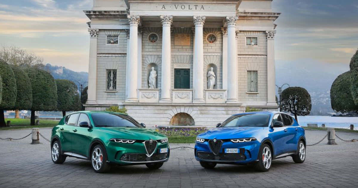愛快羅密歐 桌布 壁紙 — 兩輛時尚的Alfa Romeo SUV，綠色和藍色，停在一座擁有柱子和雕像的宏偉新古典主義別墅前。