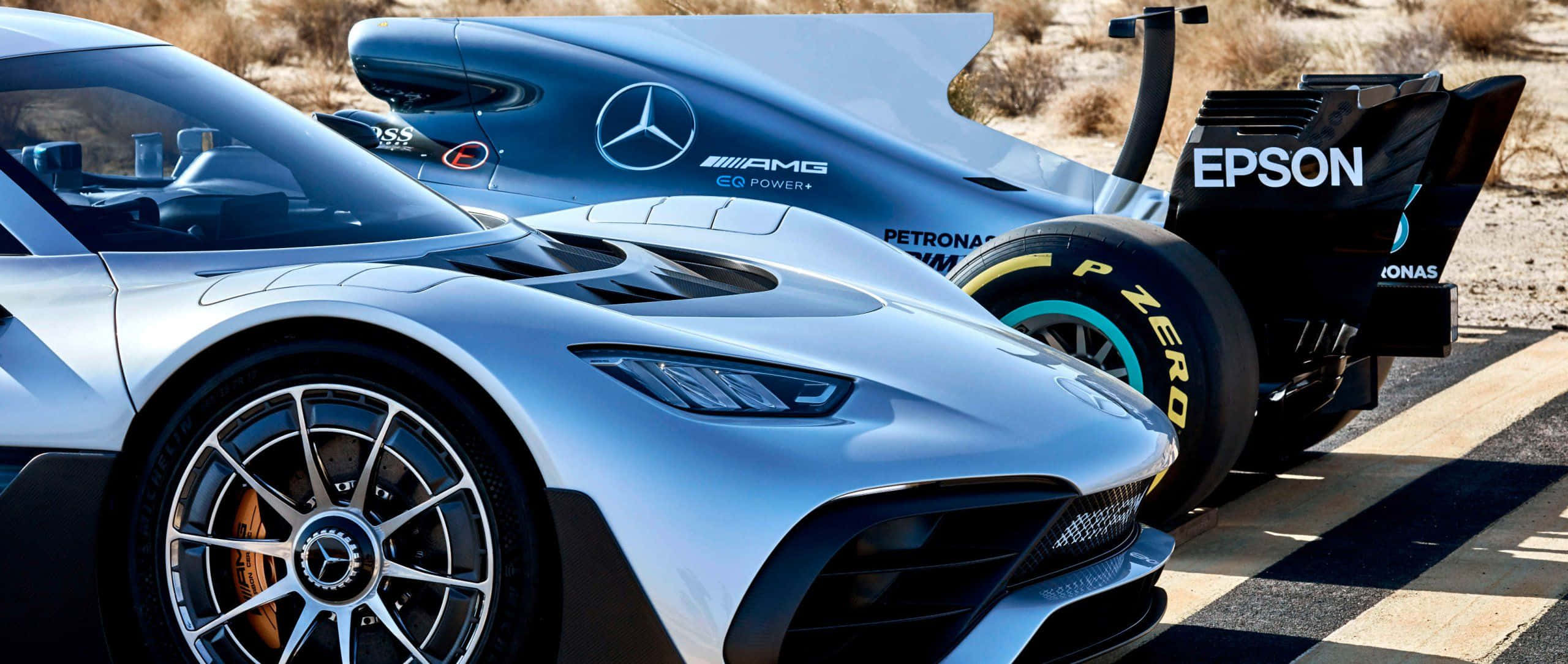 Mercedes 桌布 壁紙 — 兩輛時尚的銀藍色 Mercedes-AMG 賽車配備 Pirelli 輪胎，在明亮的陽光下停泊在沙漠賽道上。