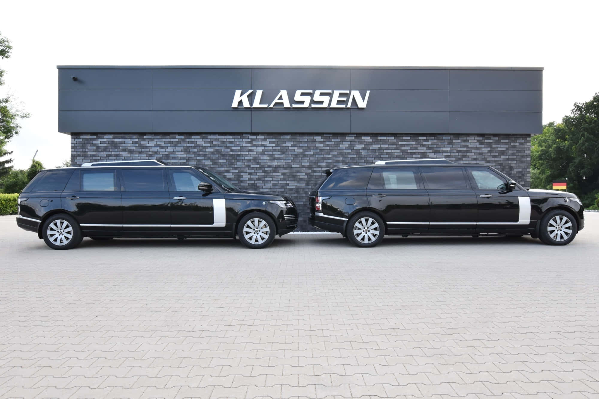 Range Rover 桌布 壁紙 — 兩輛時尚的黑色加長版Range Rover並排停放在現代化的KLASSEN展示中心大樓前。