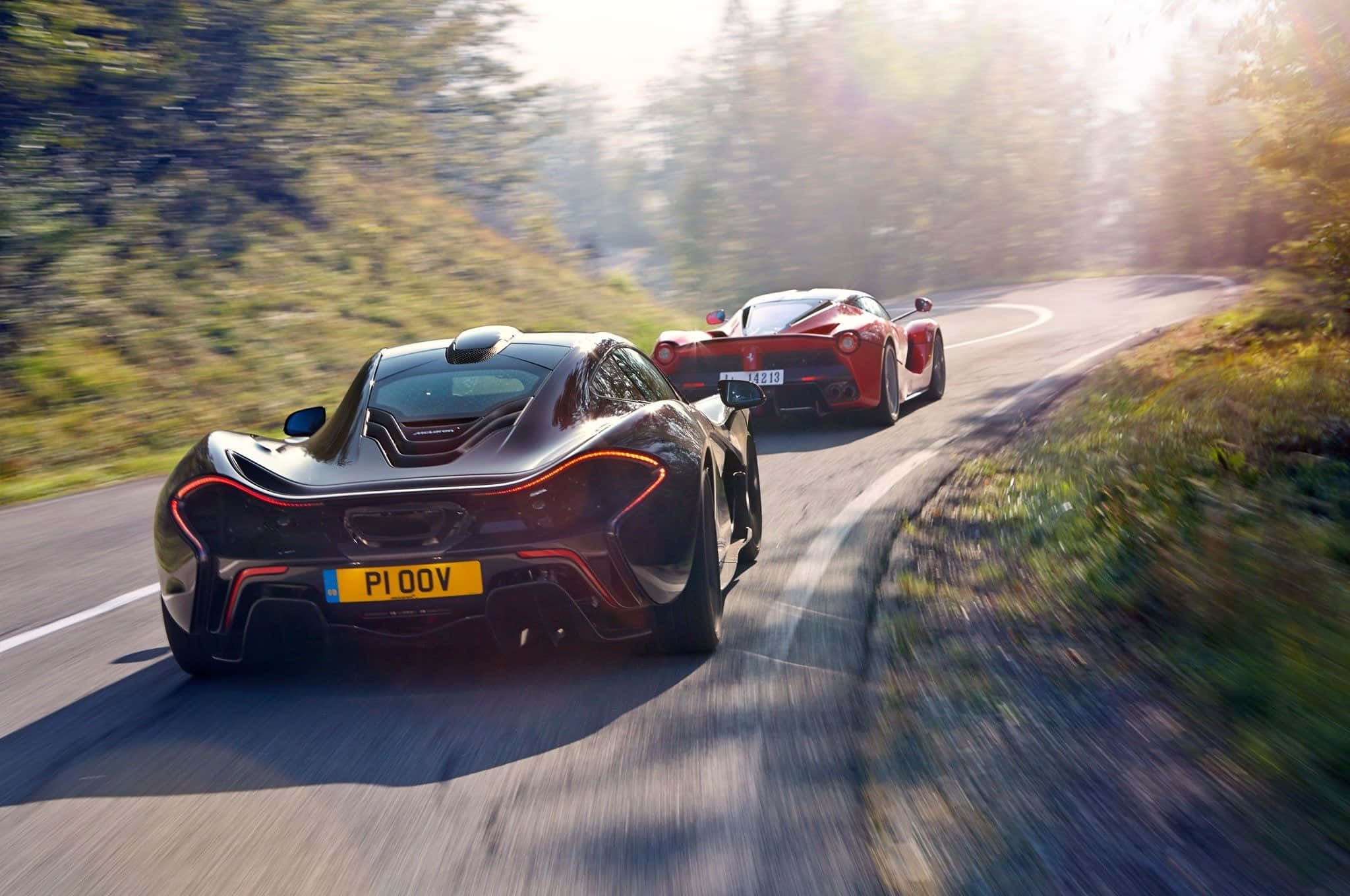 Ferrari Laferrari 桌布 壁紙 — 兩輛時尚超級跑車沿著蜿蜒的森林道路奔馳，沐浴在金色陽光下。