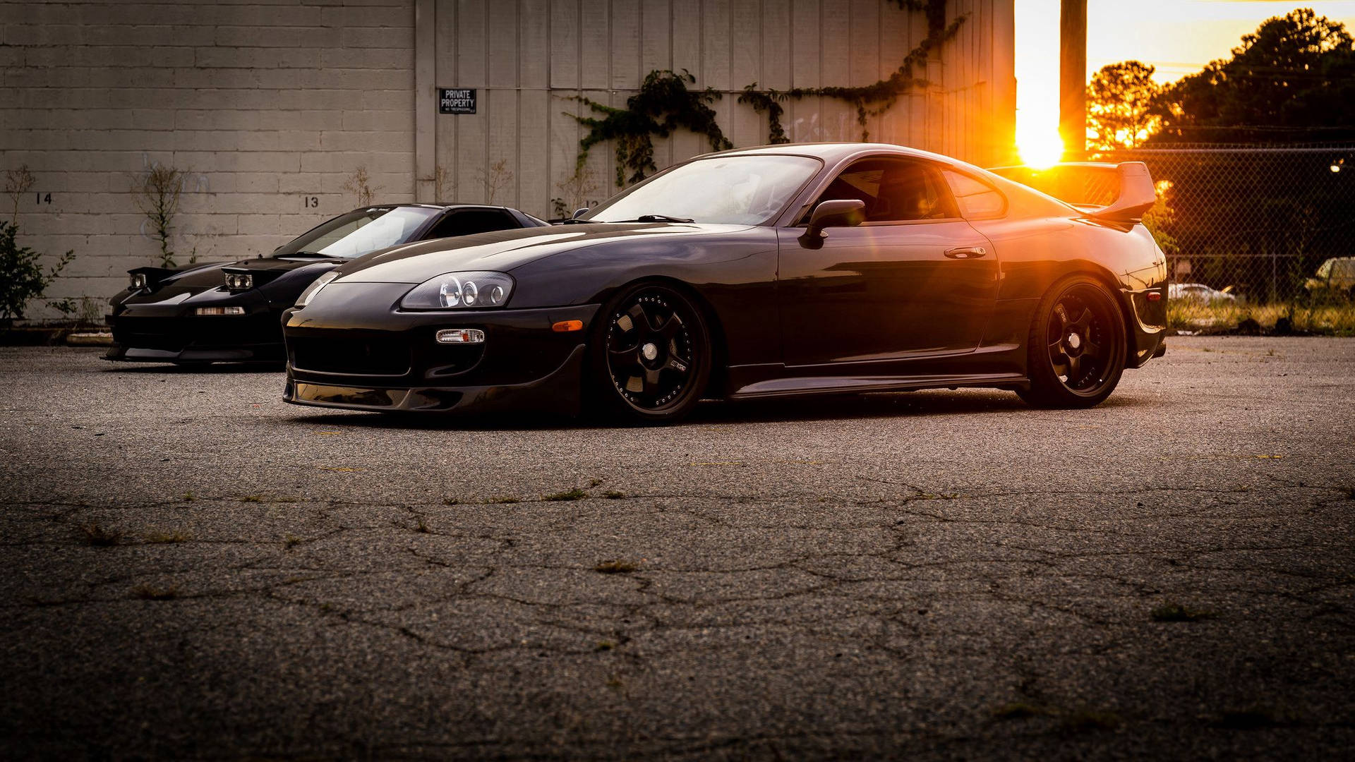 日落時分，兩輛黑色跑車停泊在都市空地。 — Toyota Supra Mk4 壁紙