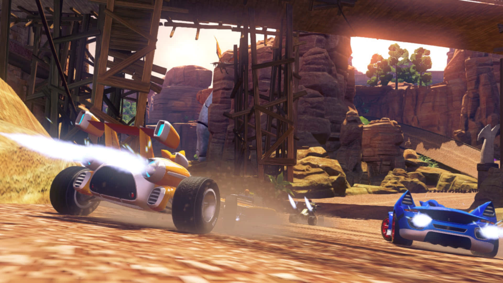 Sonic And All-stars Racing Transformed 桌布 壁紙 — 兩輛未來主義賽車在日落時分穿越塵土飛揚的沙漠峽谷，引擎發光，頭頂有木製鷹架。