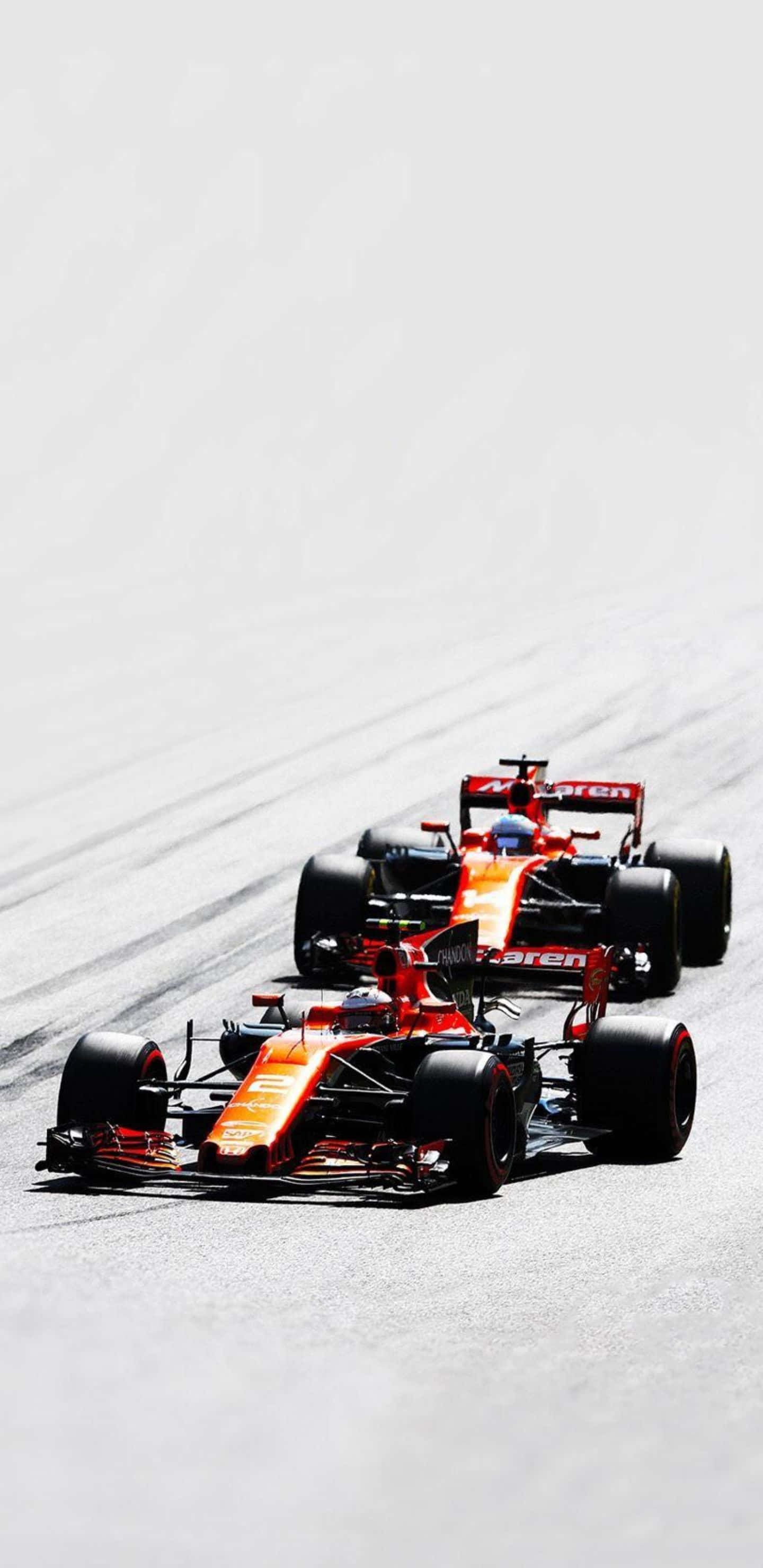 Formula 1 桌布 壁紙 — 兩輛橙色和紅色的F1賽車在陽光明媚的賽道上緊密競賽，輪胎痕跡清晰可見。