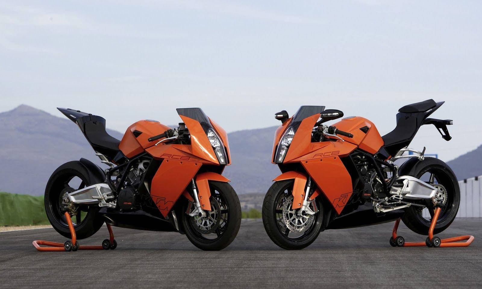 KTM 摩托車 桌布 壁紙 — 兩輛流線型橙色KTM RC8摩托車並排停在鋪砌路面上，遠山在淡白天空下。