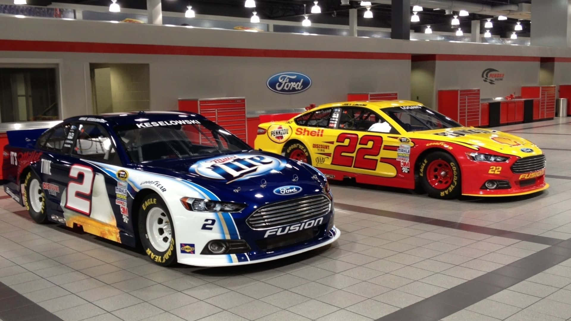nascar 桌布 壁紙 — 兩輛福特NASCAR賽車（編號2和22）在室內明亮燈光下展示。