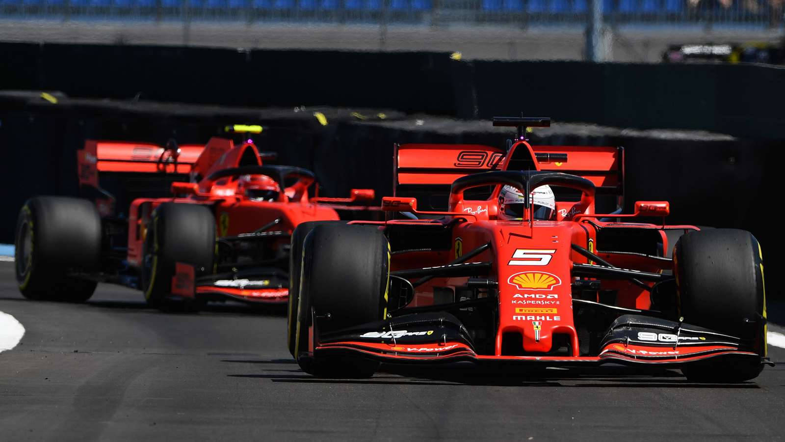 Formula One 桌布 壁紙 — 兩輛紅色法拉利一級方程式賽車並排奔馳在陽光普照的賽道上，黑色輪胎和贊助商標誌清晰可見。