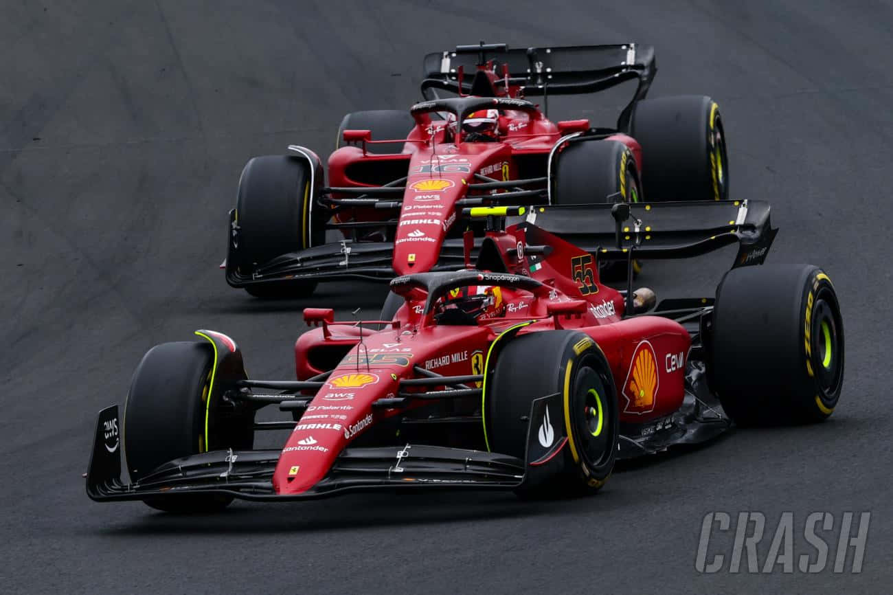 F1 桌布 壁紙 — 兩輛紅色法拉利一級方程式賽車在潮濕賽道上緊密競賽，可見「CRASH」浮水印。