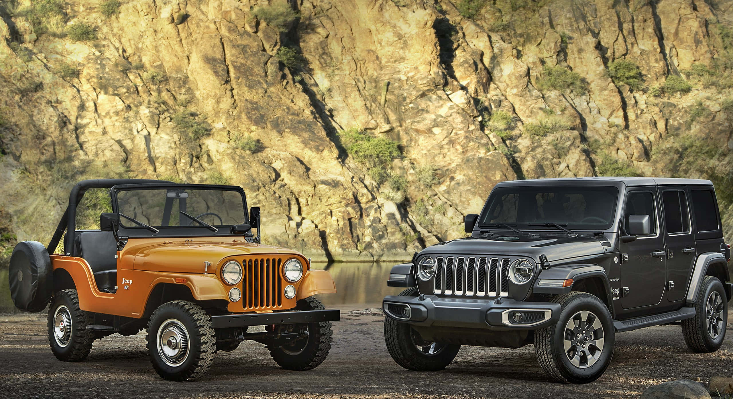 Jeep Cj 桌布 壁紙 — 兩輛經典與現代Jeep Wrangler並排停泊在岩石河岸，背後是崎嶇的懸崖。