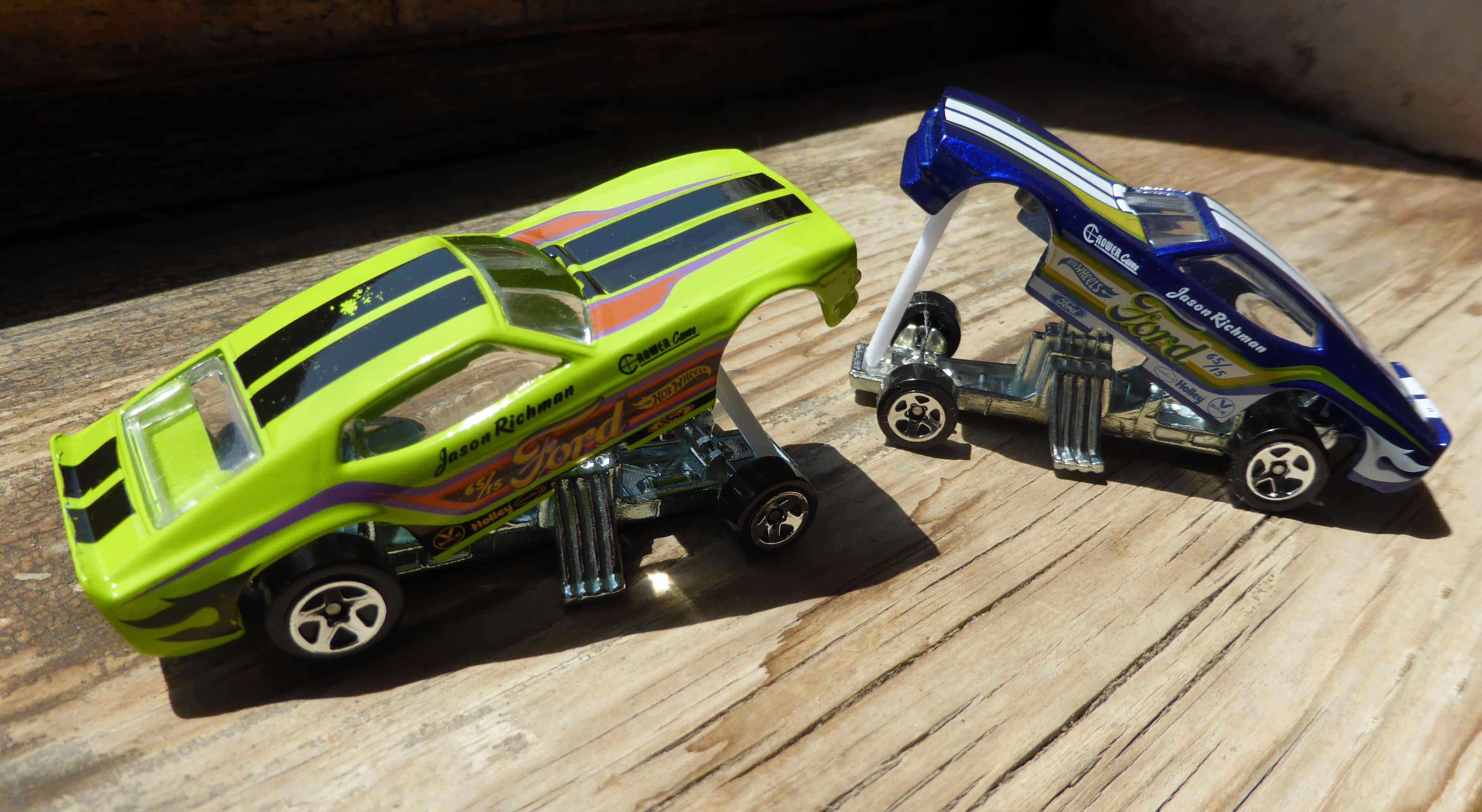 cars 桌布 壁紙 — 兩輛色彩鮮豔的熱棒玩具車，帶有定制油漆和鍍鉻細節，放在陽光照射的木質表面上。