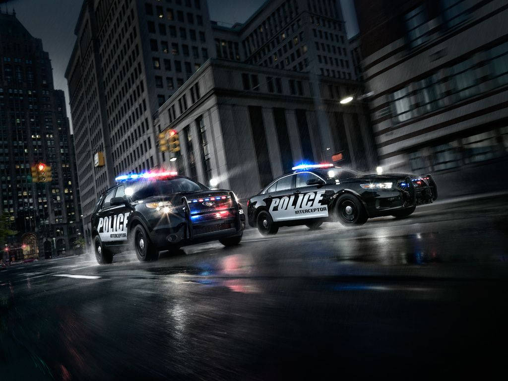 警察 桌布 壁紙 — 兩輛警車閃著警燈在夜間濕滑的街道上疾馳，車頭燈劃破潮濕的黑暗。