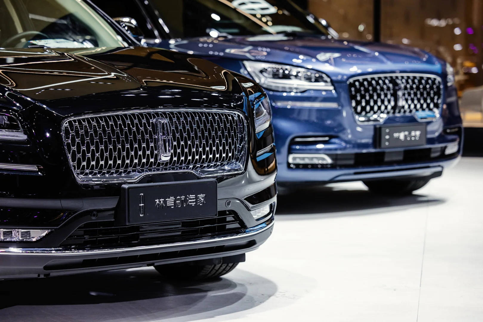 lincoln 桌布 壁紙 — 兩輛豪華SUV，配備鍍鉻格柵和時尚頭燈，在明亮的展廳燈光下展示。