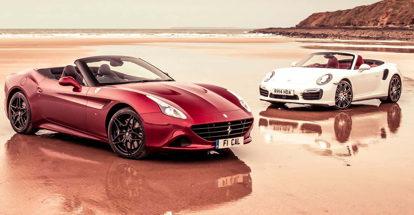 Ferrari California T 桌布 壁紙 — 兩輛豪華敞篷車，一輛紅色法拉利和一輛白色保時捷，停在潮濕的沙灘上，倒映在淺水中。