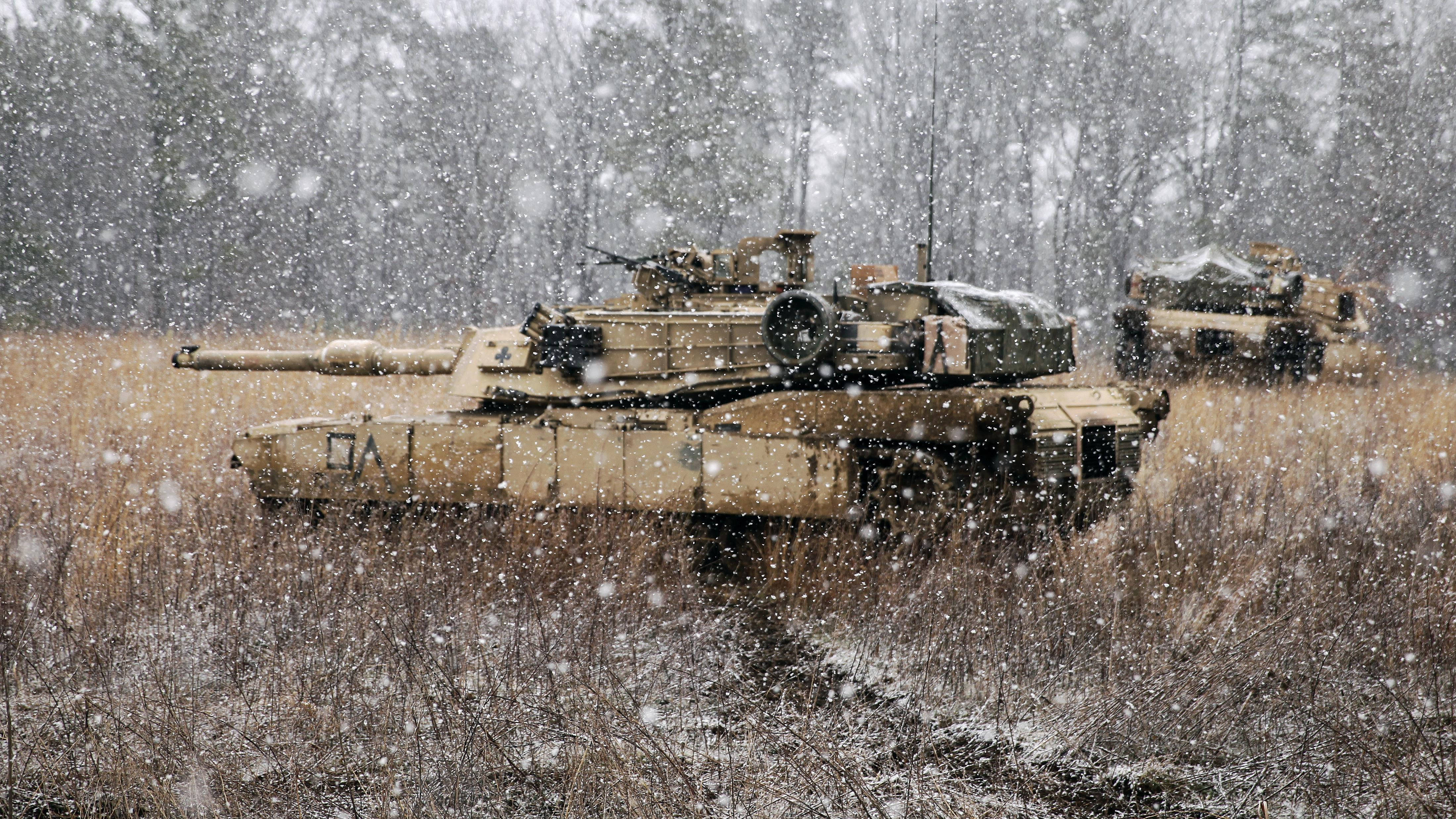 Tanks 桌布 壁紙 — 兩輛軍用坦克靜止在雪地上，背後有光禿禿的樹木，大雪紛飛。