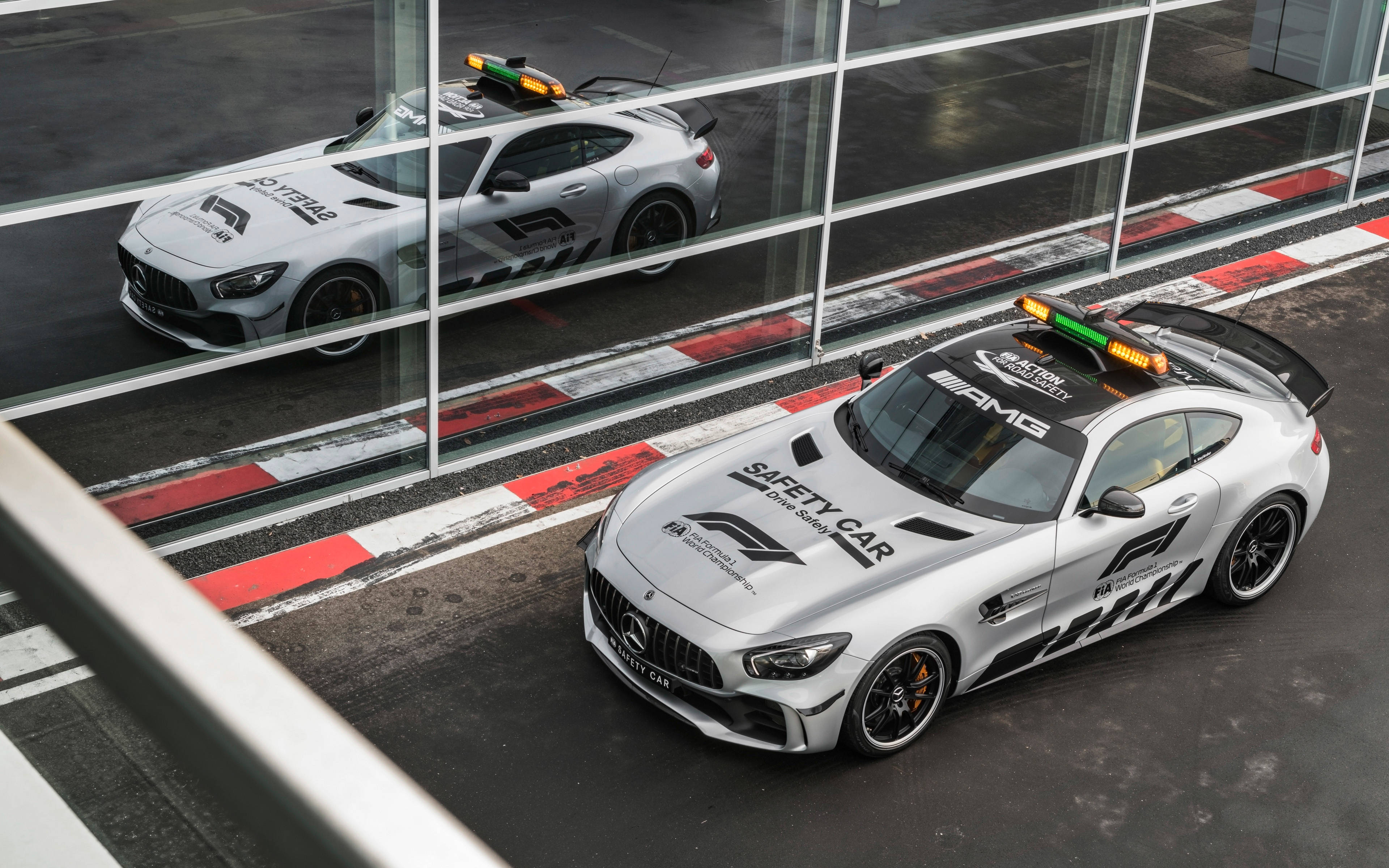 Gtr 桌布 壁紙 — 兩輛銀色梅賽德斯-AMG GT安全車，閃爍著燈光，停在賽道旁的玻璃屏障邊。