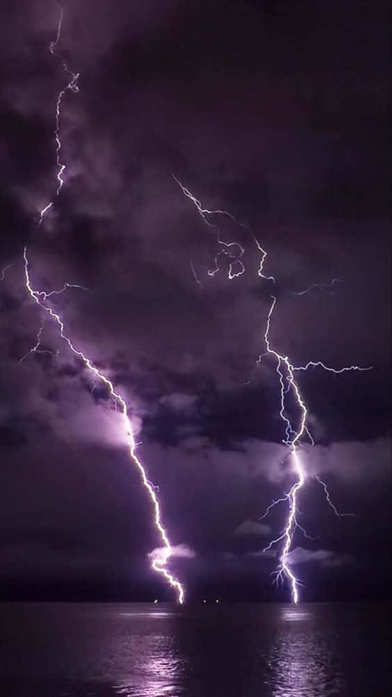 閃電 桌布 壁紙 — 兩道巨大的紫色閃電從暴風雨的夜空劈落到黑暗的水面上。