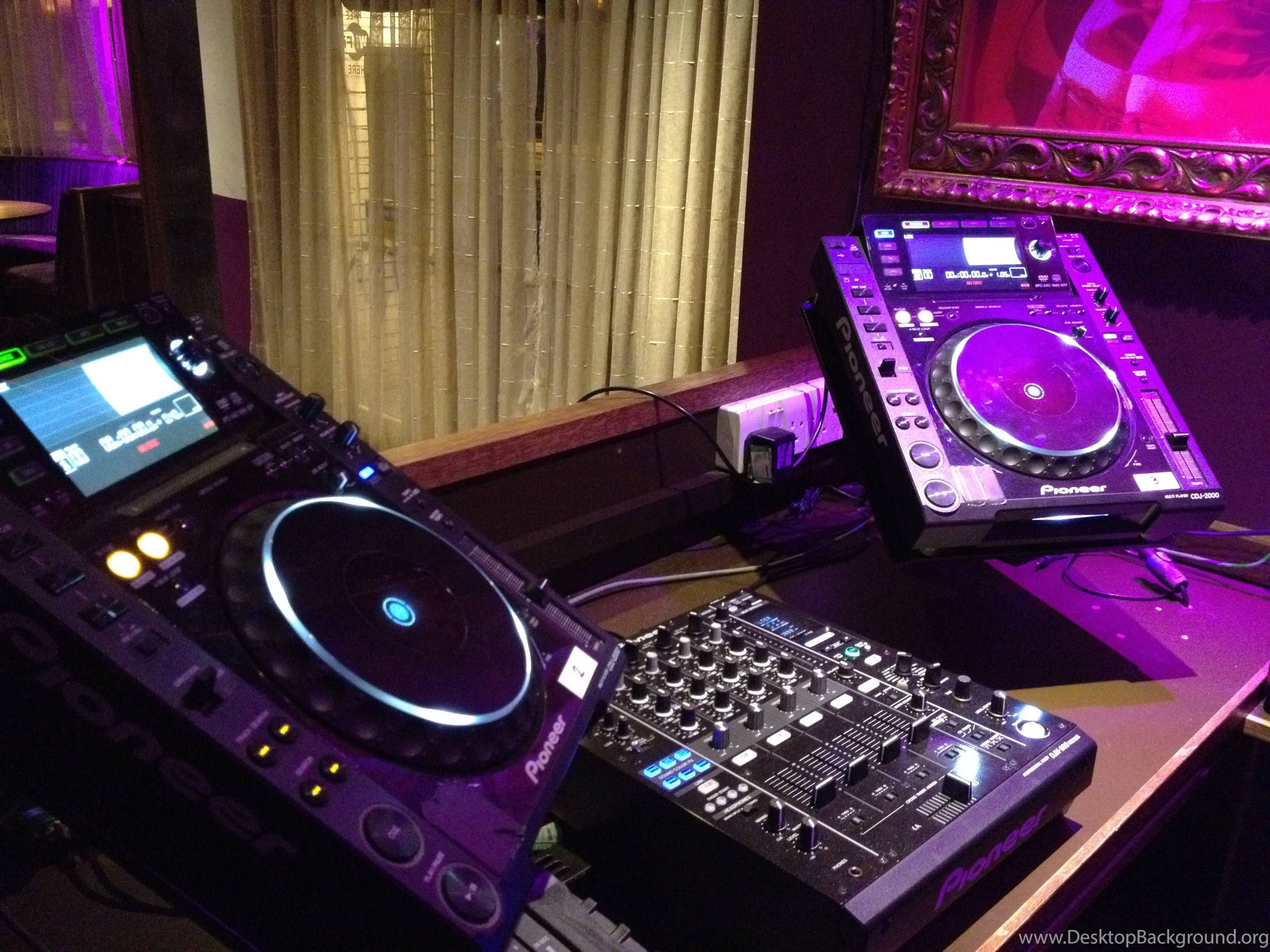 DJ 桌布 壁紙 — 兩部Pioneer DJ唱盤和混音器在黑暗舞台上沐浴在紫色燈光中，背景有竹簾。
