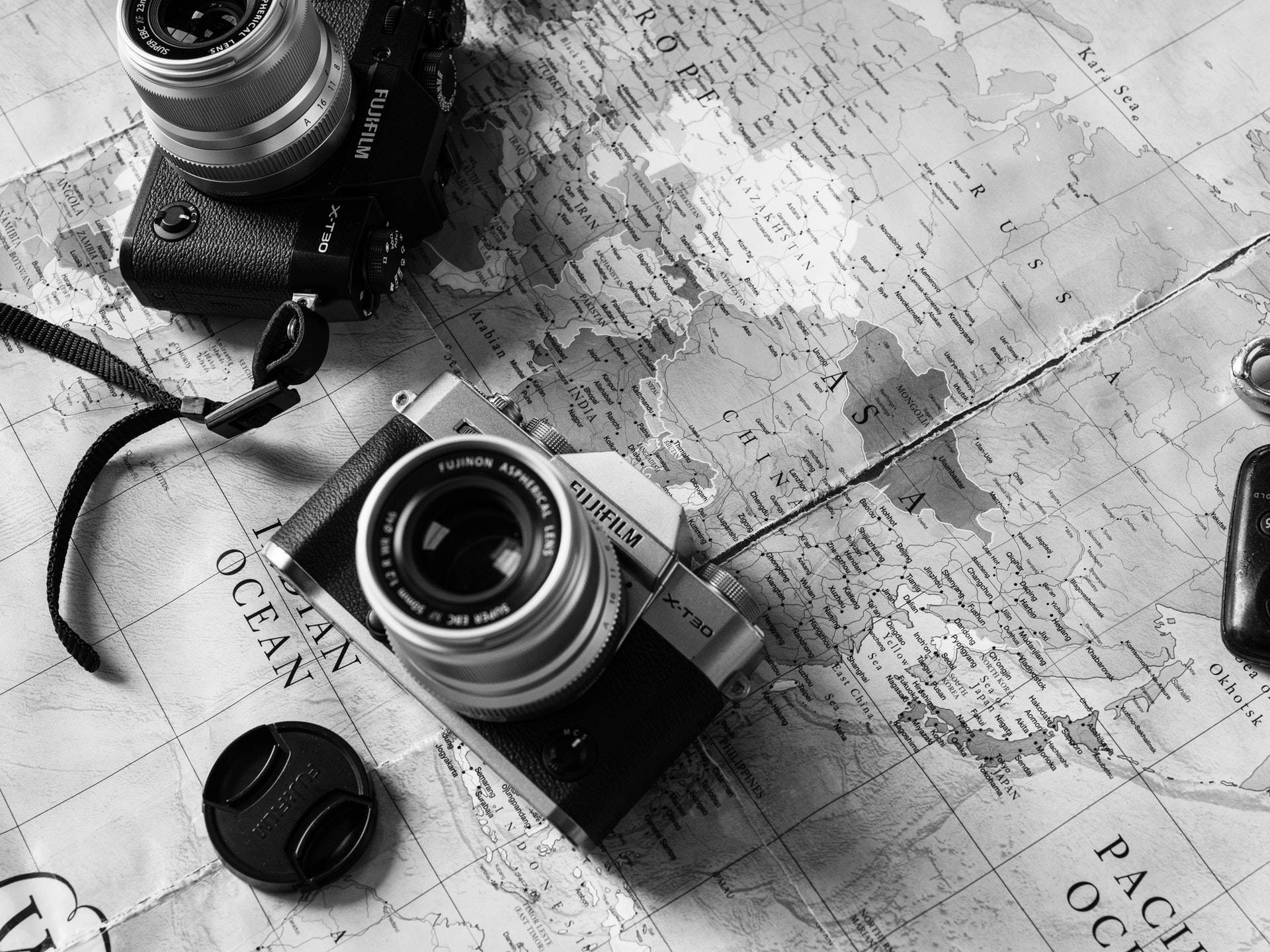 Map 桌布 壁紙 — 兩部復古Fujifilm相機放在詳細的單色世界地圖上，喚起旅行慾望和攝影冒險。