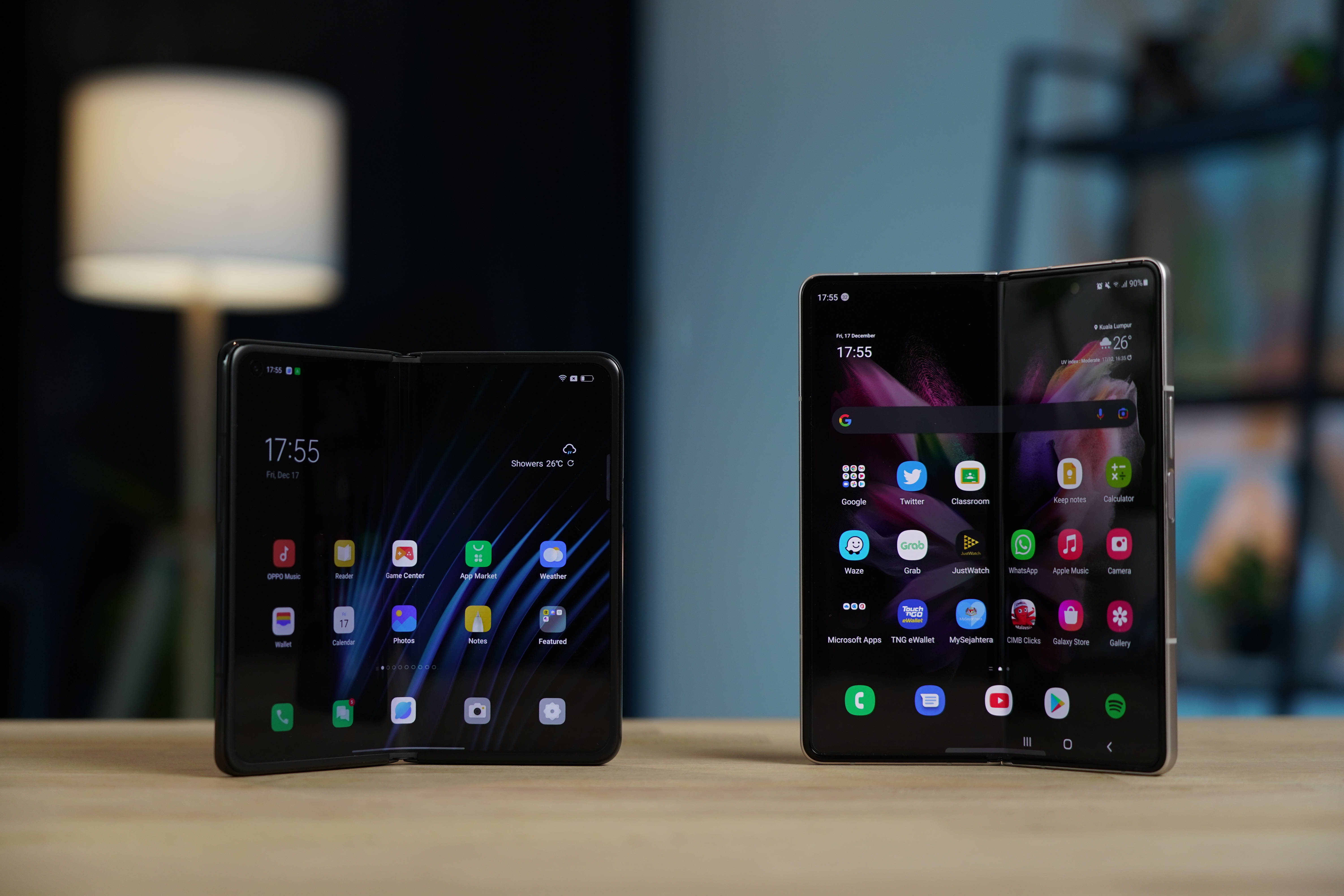 oppo 桌布 壁紙 — 兩部時尚摺疊智慧型手機在木桌上打開展示，旁邊有柔和燈光的燈和模糊背景。