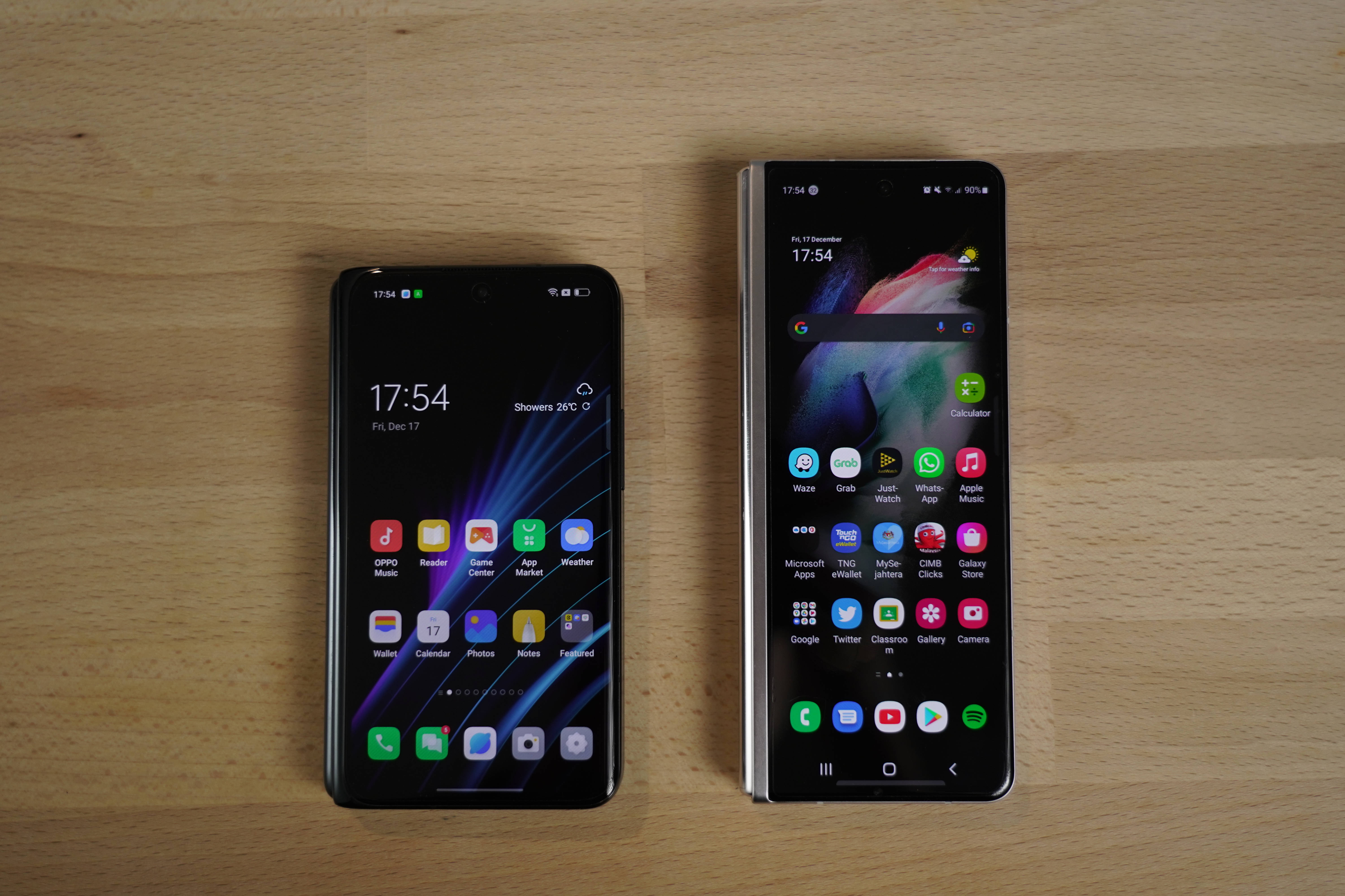 oppo 桌布 壁紙 — 兩部現代智慧型手機，一部摺疊、一部展開，並排放在淺色木質表面上，顯示充滿活力的主畫面。