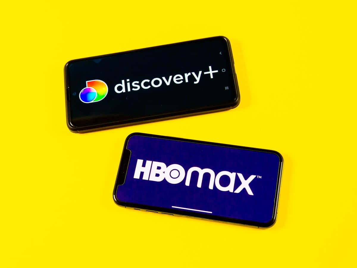HBO 桌布 壁紙 — 兩部顯示Discovery+和HBO Max標誌的智慧型手機放在鮮黃色背景上。