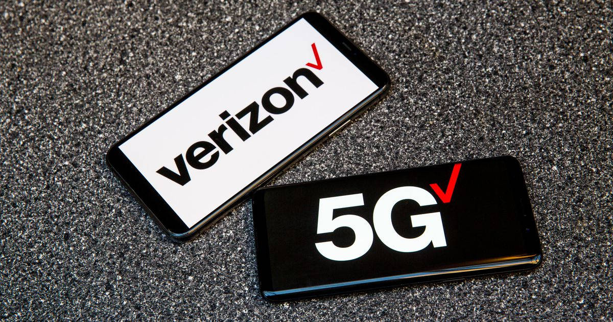 Verizon 桌布 壁紙 — 兩部顯示Verizon和5G標誌的智慧型手機放在有紋理的灰色表面上。