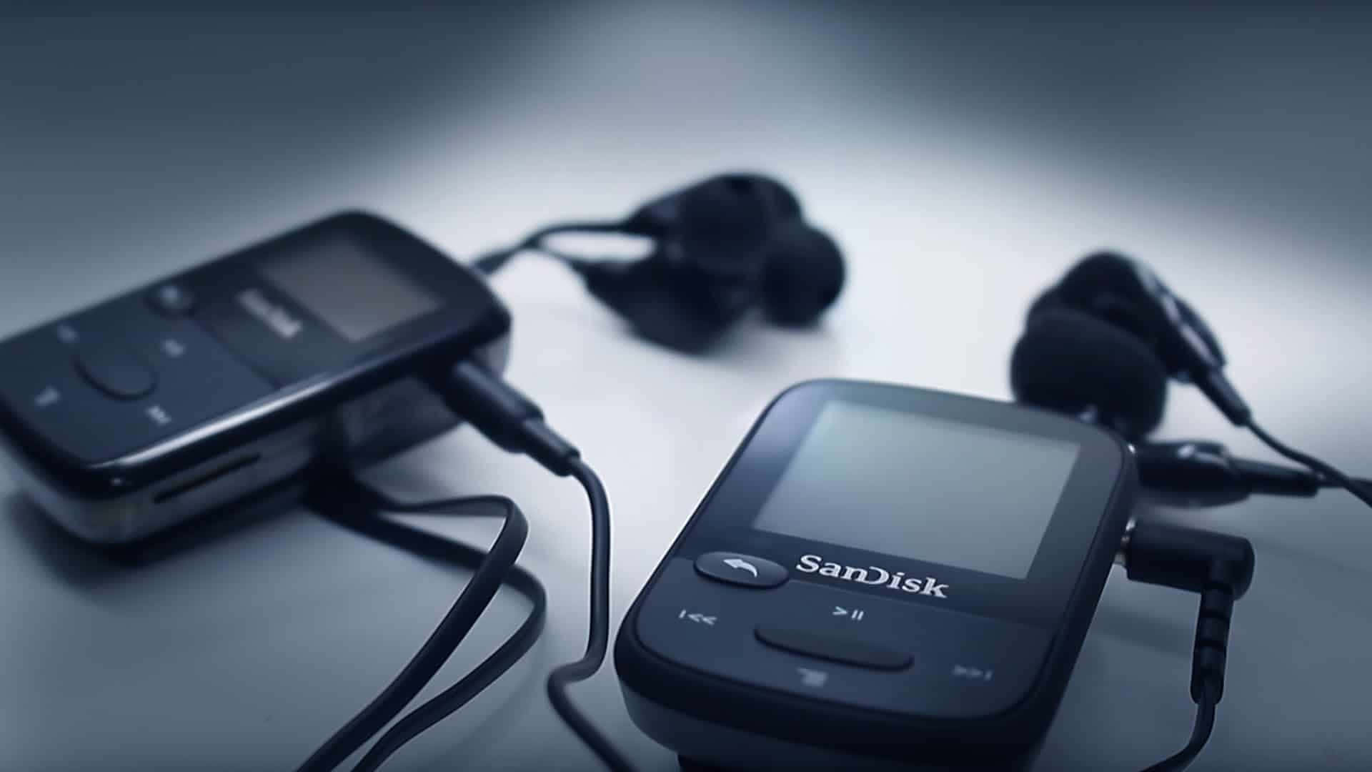 Music Player 桌布 壁紙 — 兩部黑色SanDisk MP3播放器連耳塞，在冷色燈光下放置於柔和的漸變表面上。